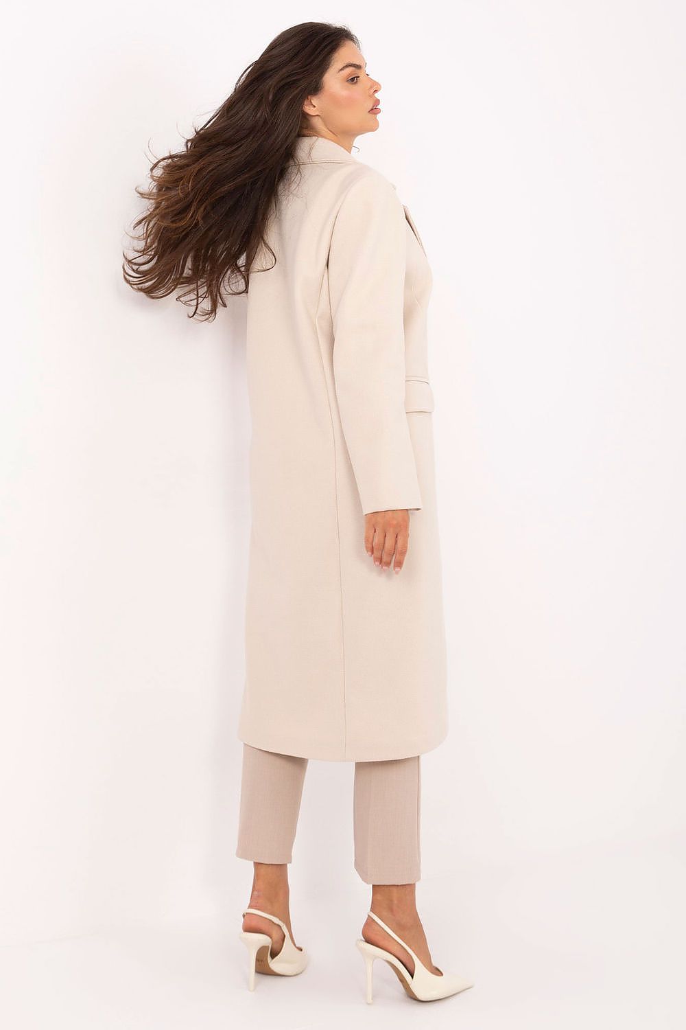 Woman wearing a long cream coat on a white background