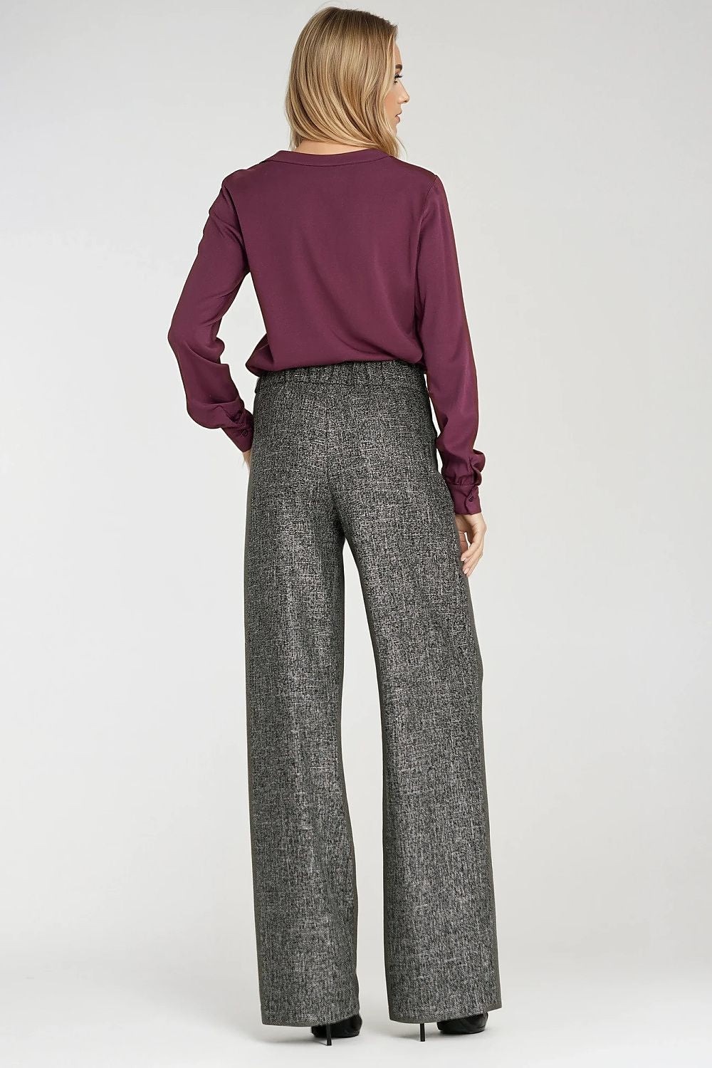 Person wearing a purple top and gray wide-leg pants on a white background