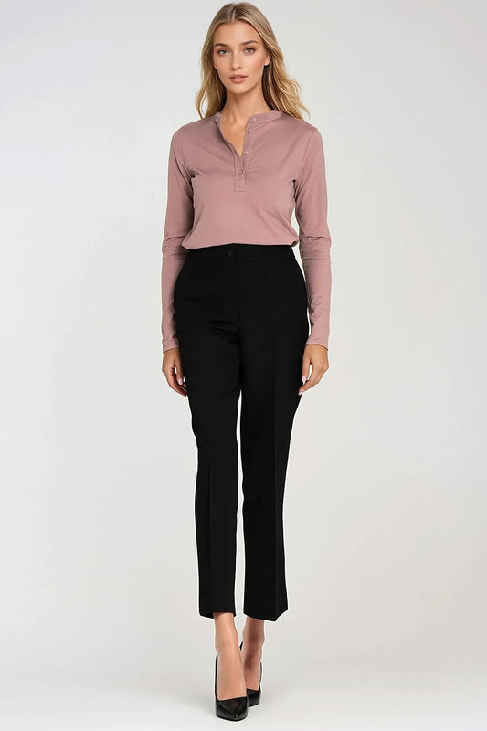 Woman wearing a mauve long-sleeve top and black pants on a white background