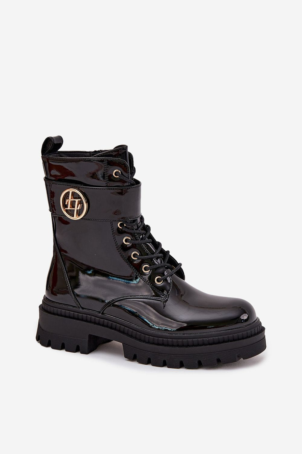  Close-up of black eco leather ankle boots with gold strap detail and platform sole.