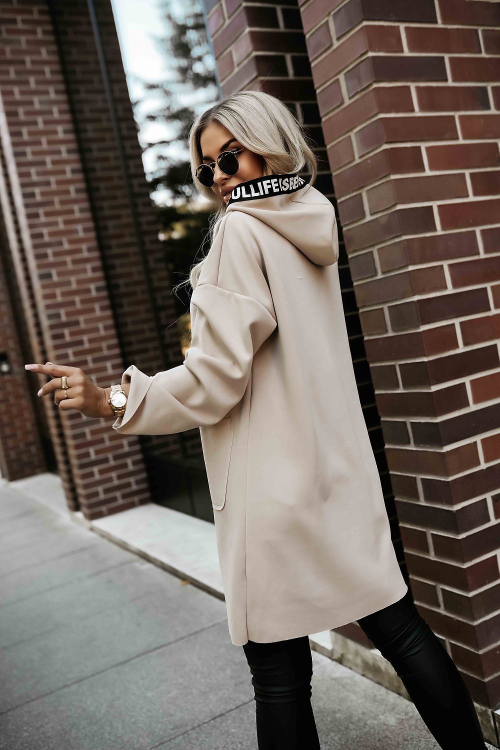 Side profile of beige hooded women’s coat highlighting loose fit and pockets.