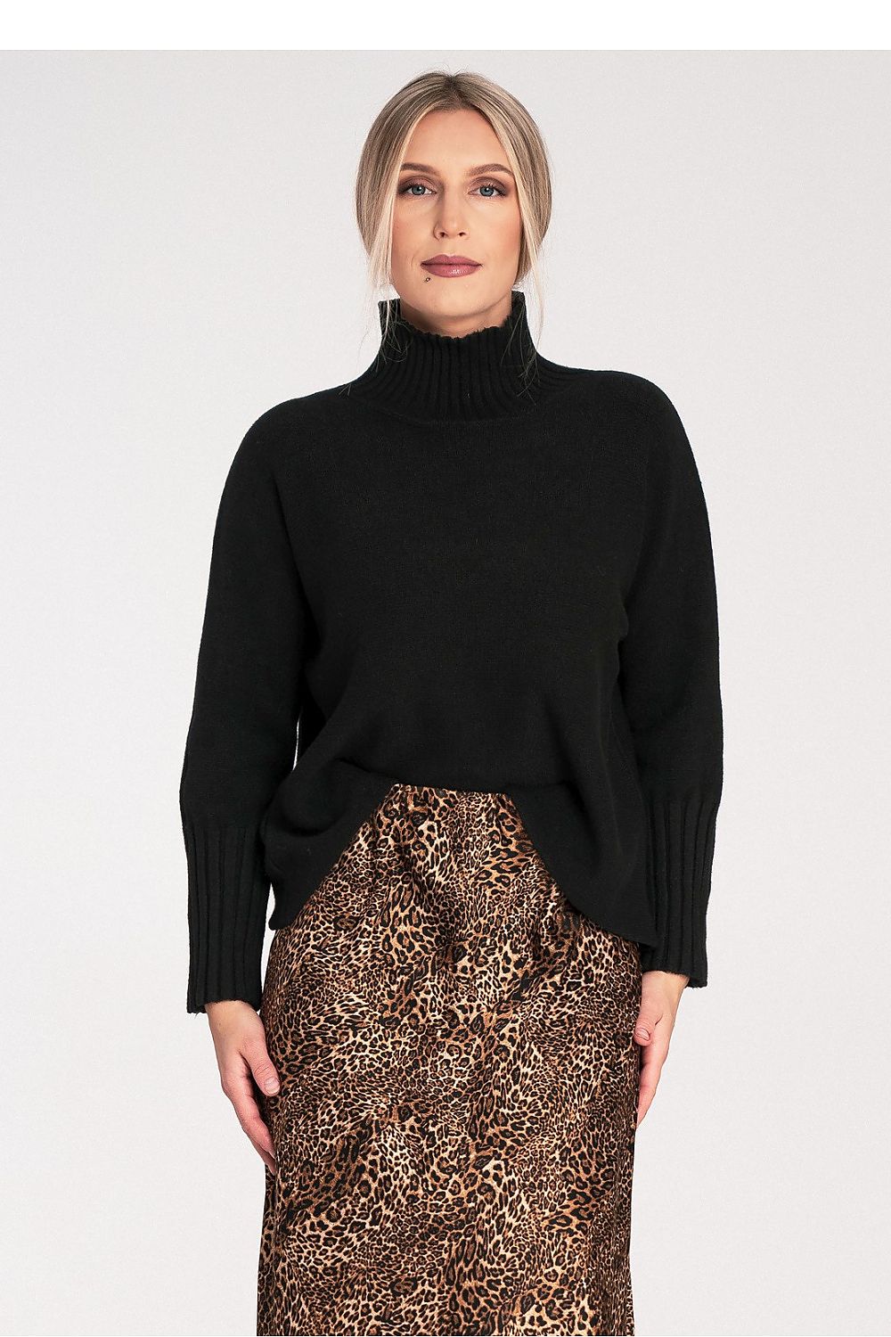 Woman wearing a black turtleneck sweater and patterned skirt on a white background