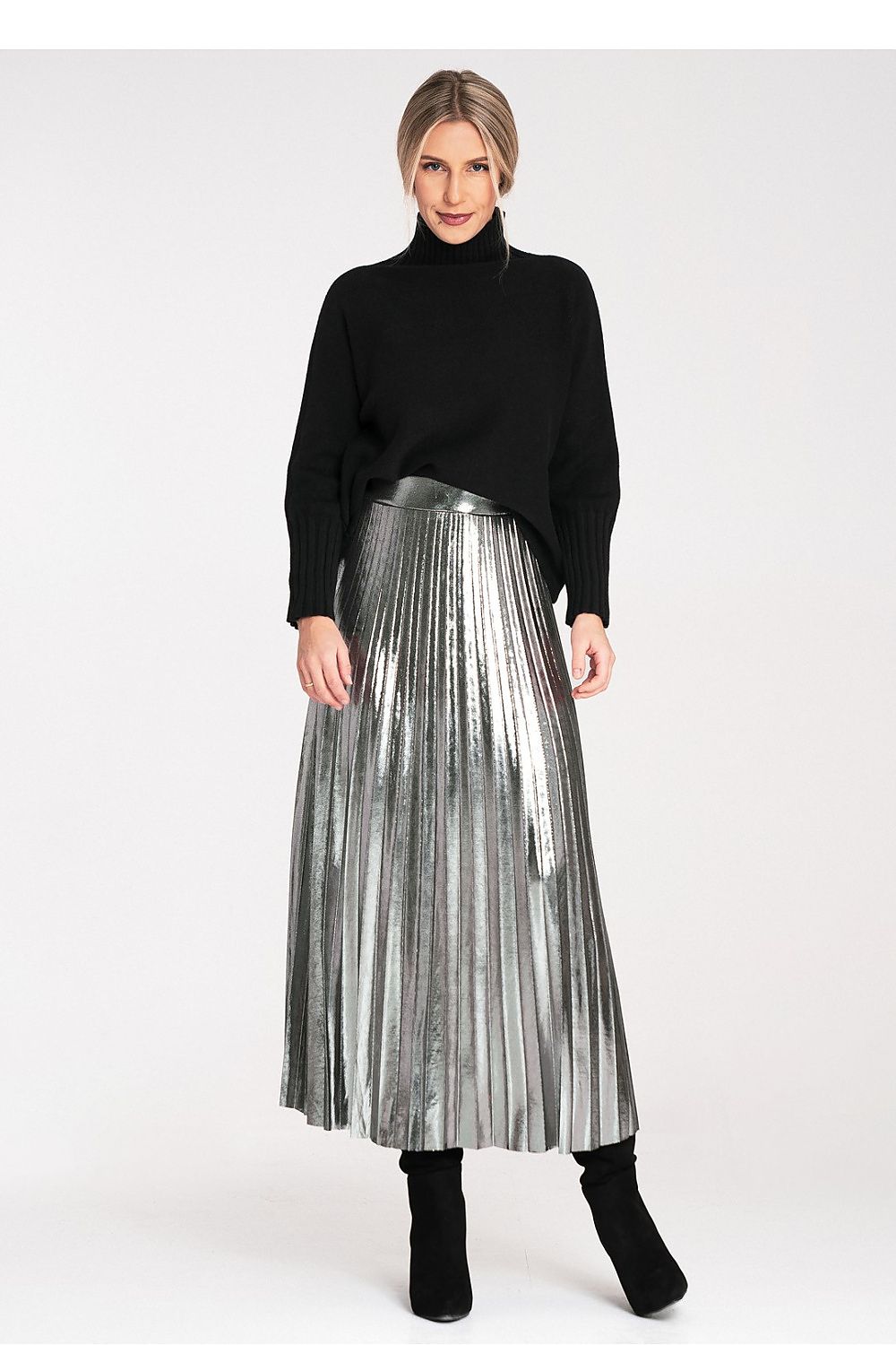 Woman wearing a black turtleneck and silver pleated skirt on a white background