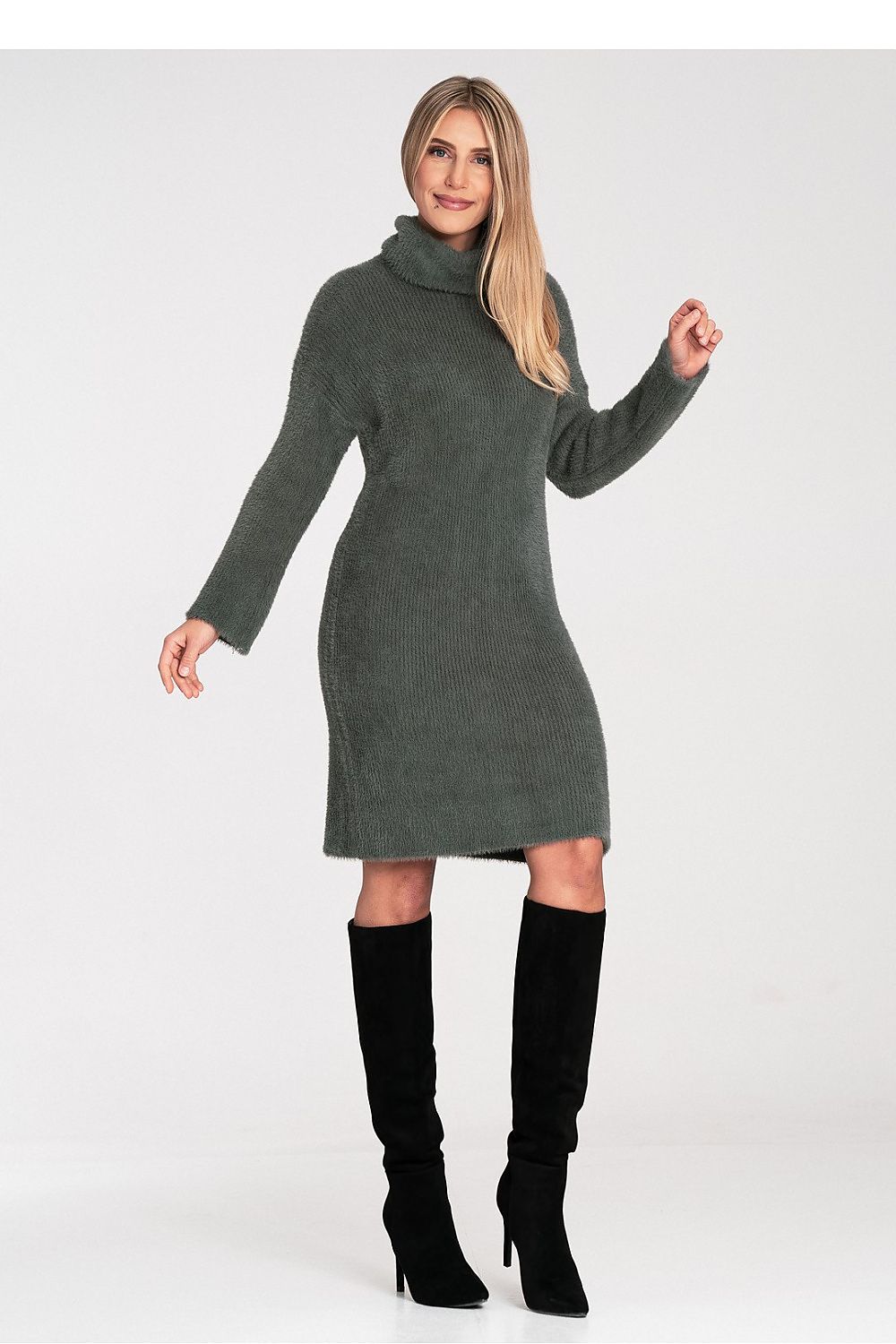 Woman wearing a green sweater dress with black knee-high boots on a white background