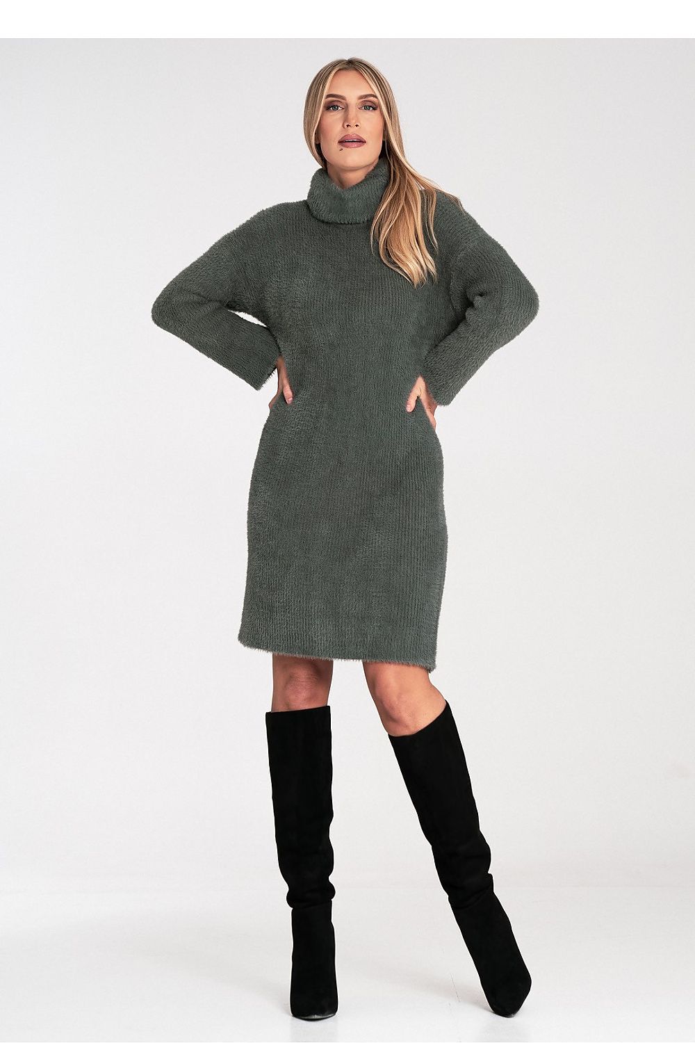 Woman wearing a green sweater dress and black knee-high boots on a white background