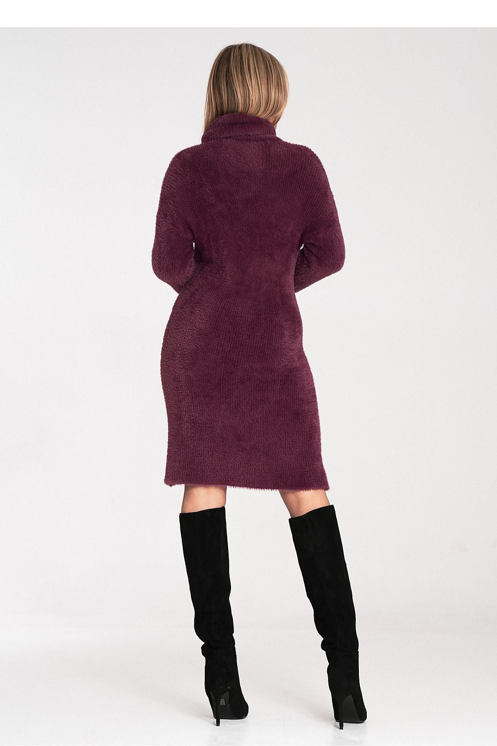 Woman wearing a burgundy dress with a high collar and black knee-high boots on a white background