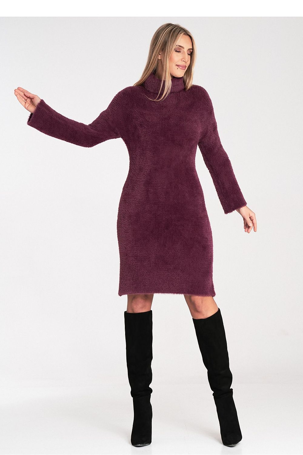 Woman wearing a burgundy dress with a high collar and black knee-high boots on a white background