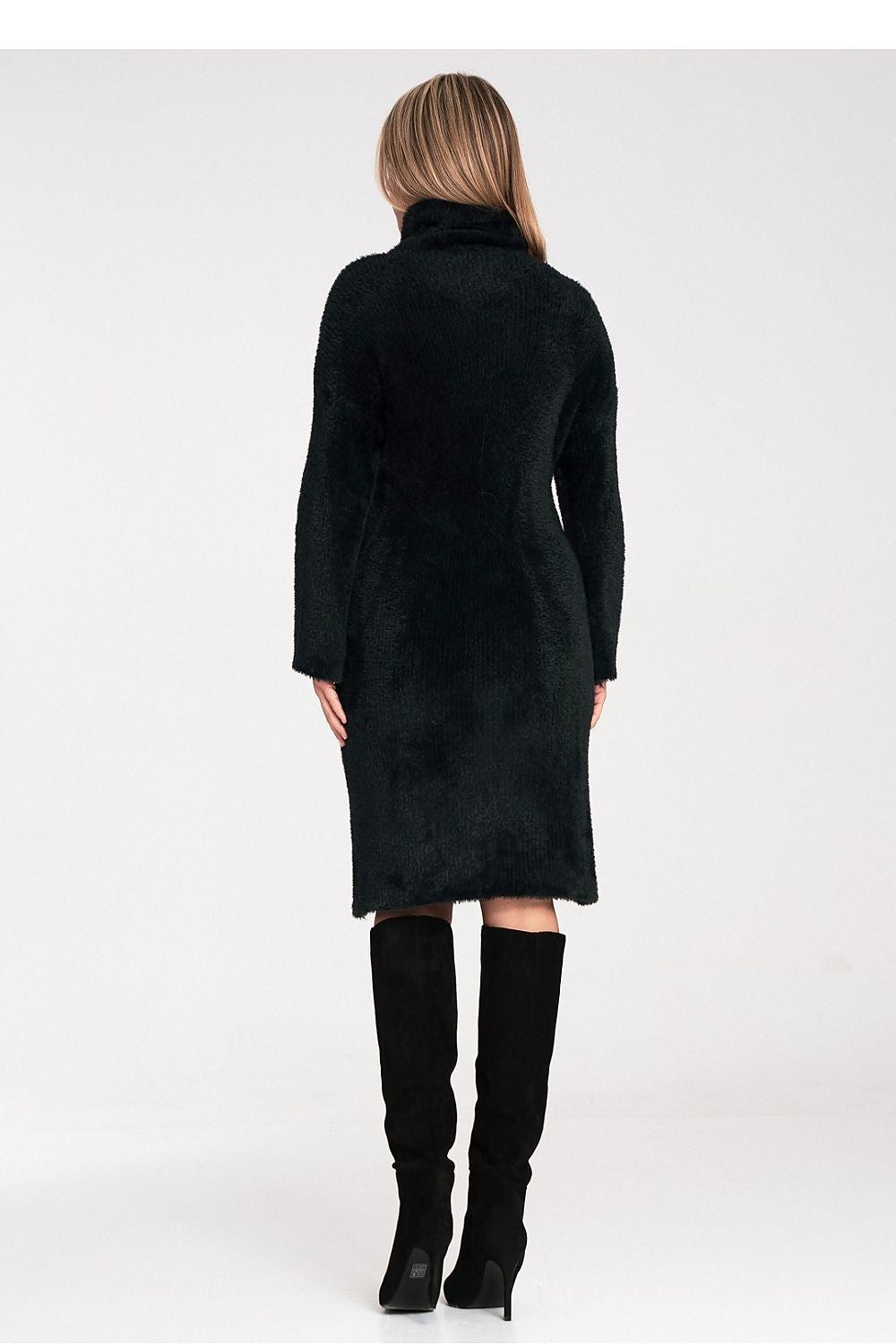 Person wearing a black coat and black boots on a white background