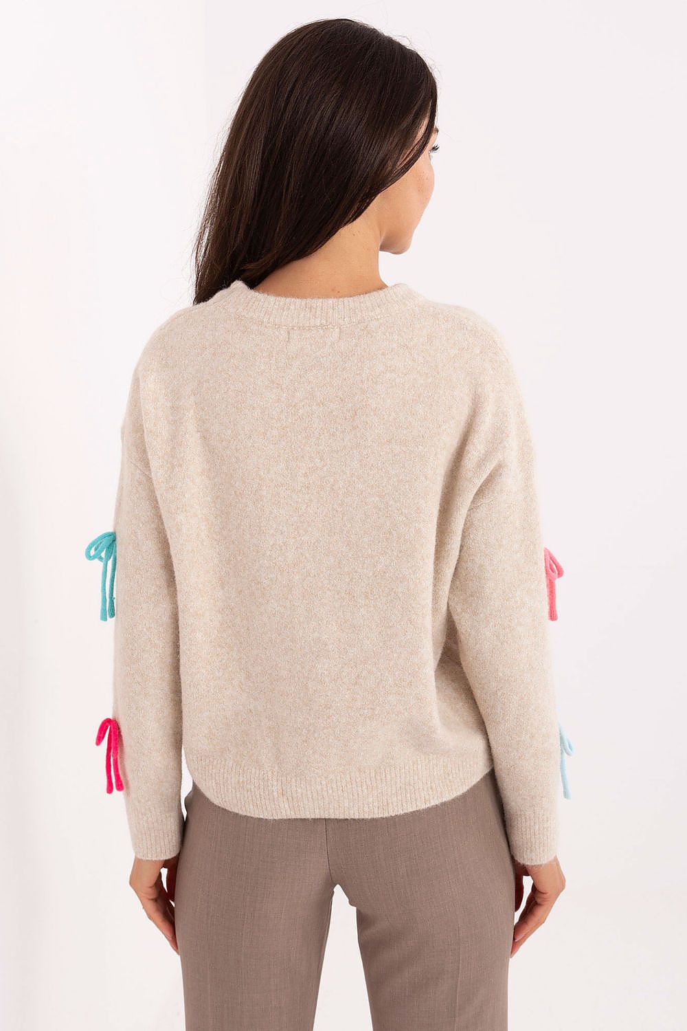 Close-up of beige sweater fabric and colorful bow details.