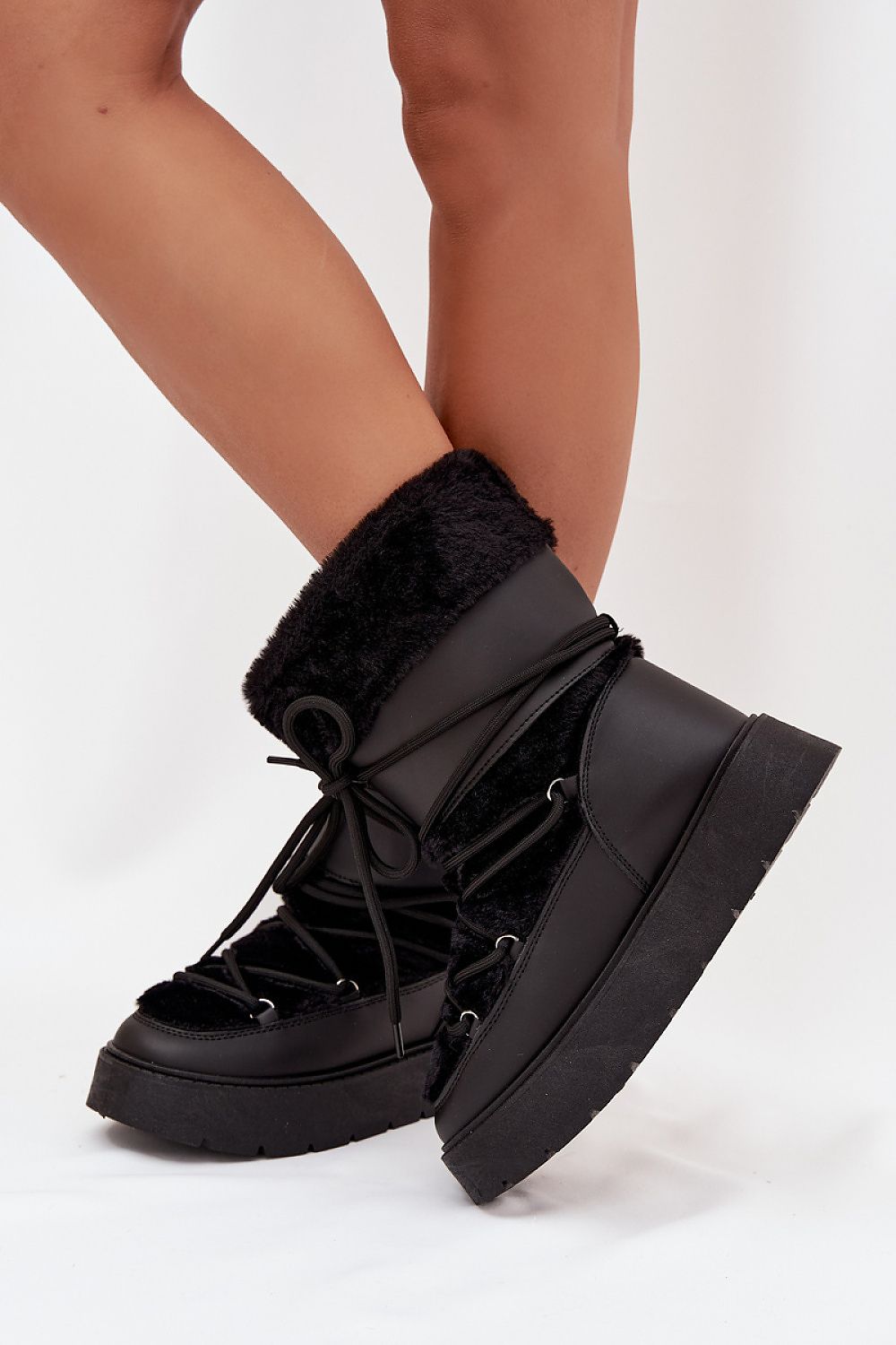 Side view of black eco leather snow boots with platform sole and warm fur trim