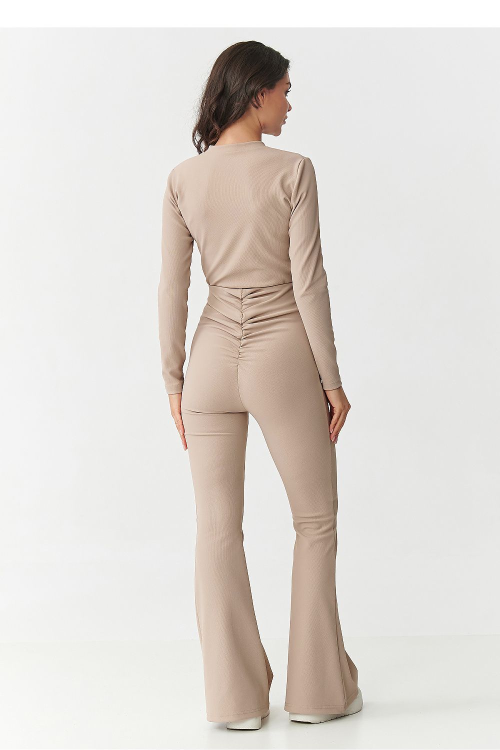 Woman wearing a beige jumpsuit on a white background