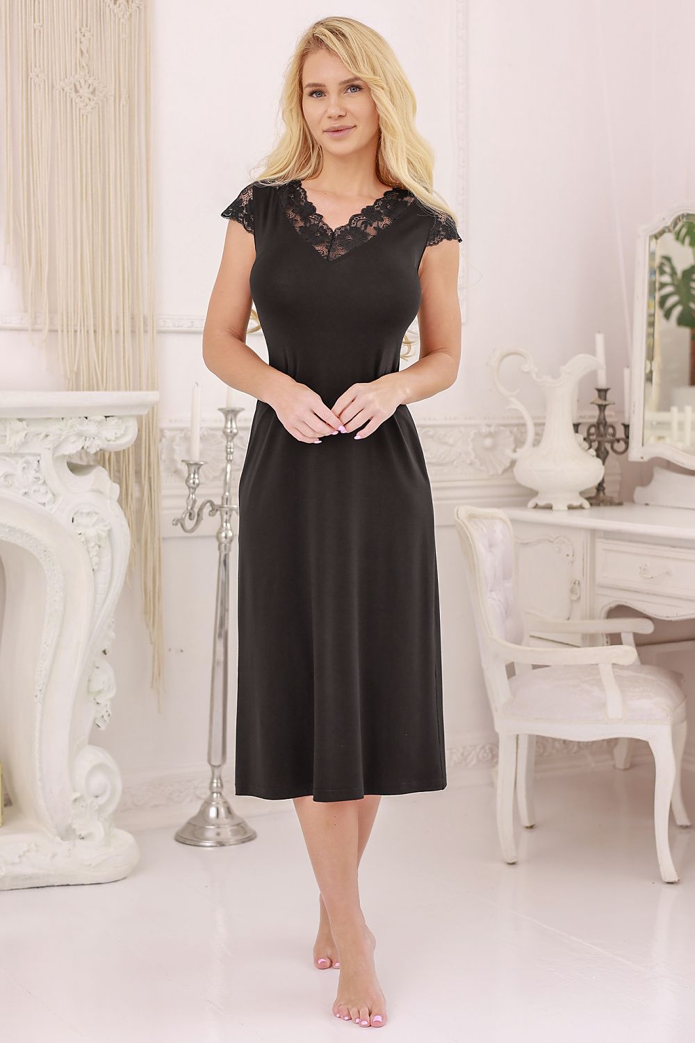 Woman wearing a black dress with lace details in an elegant room.