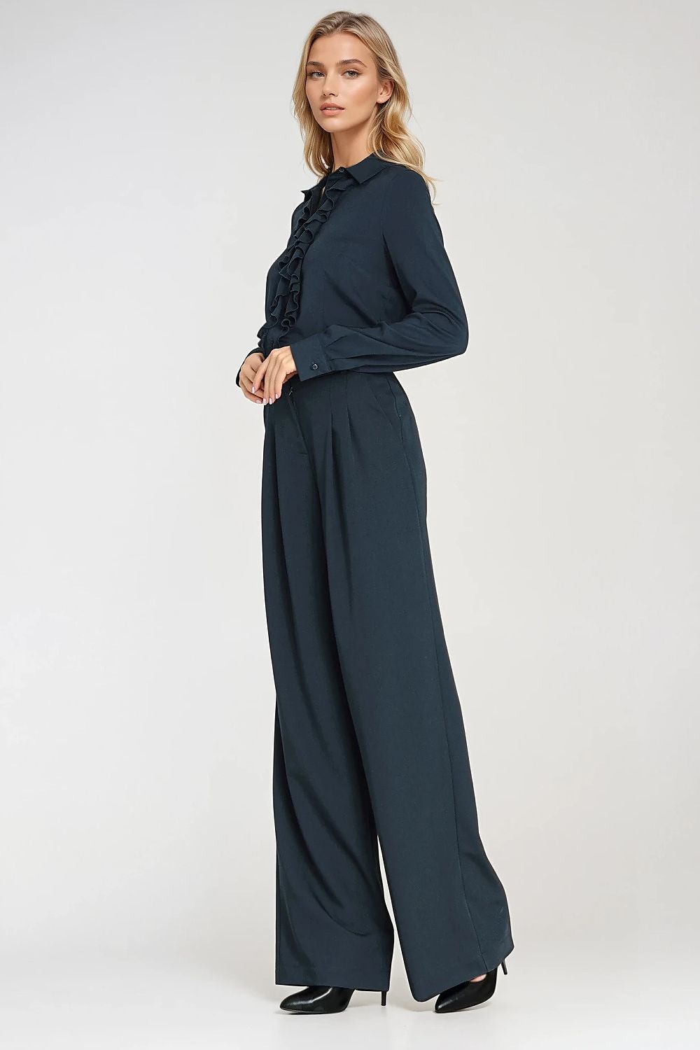 Woman wearing a dark green outfit with wide-leg pants on a white background