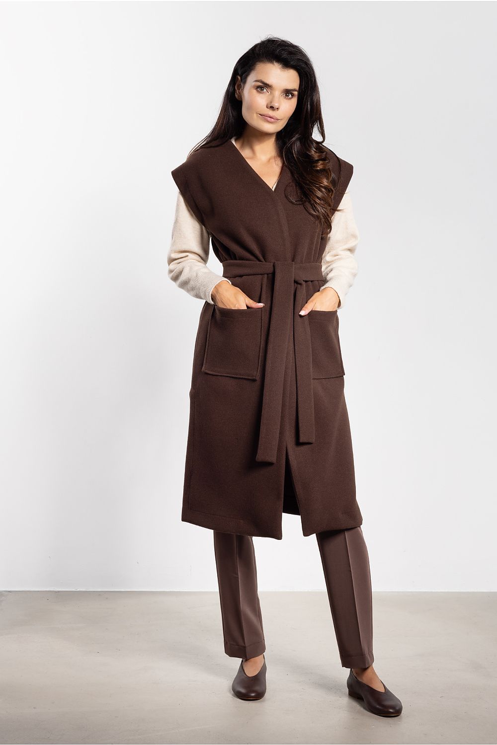 Woman wearing a brown coat and pants on a white background