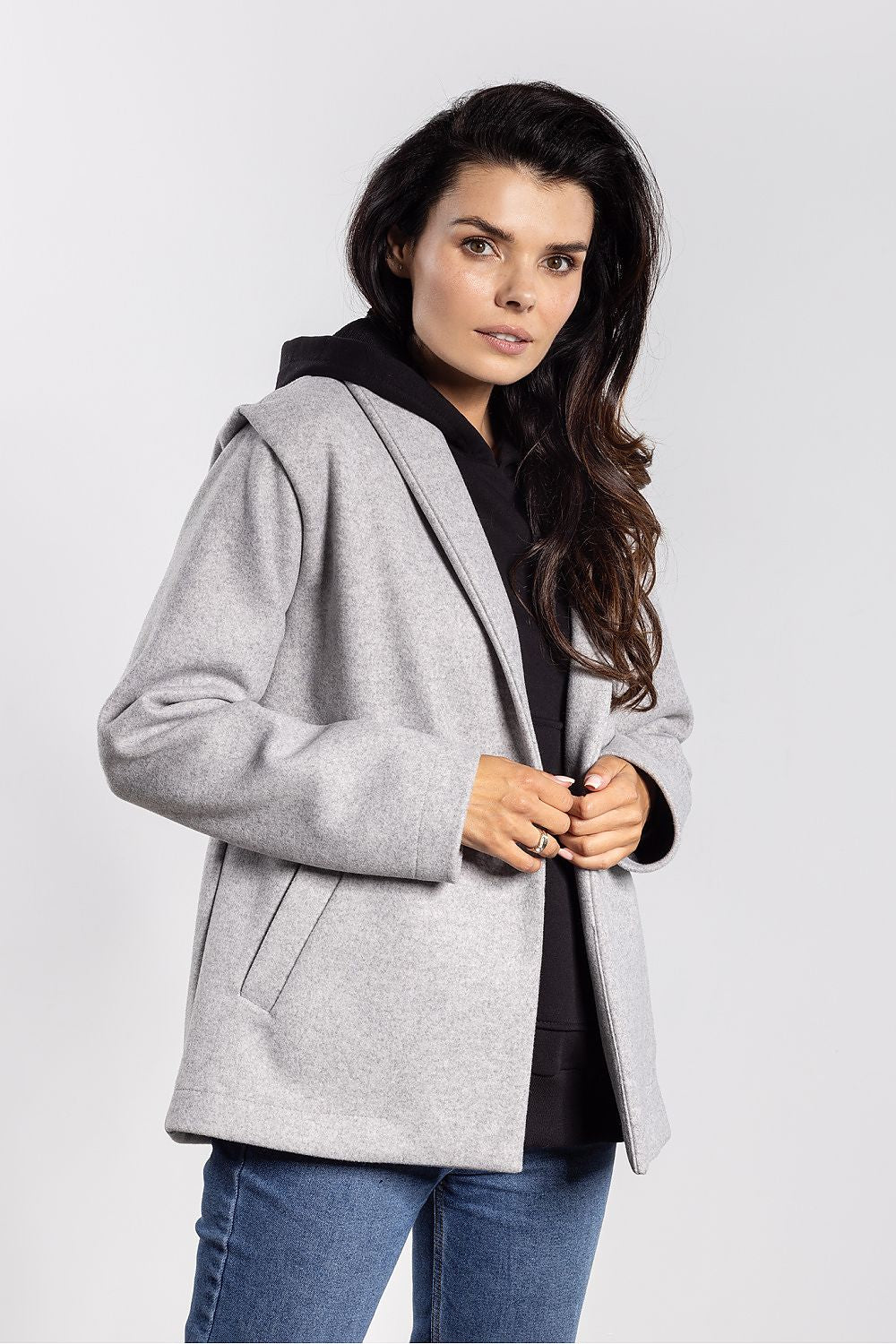 Woman wearing a gray coat over a black top on a white background