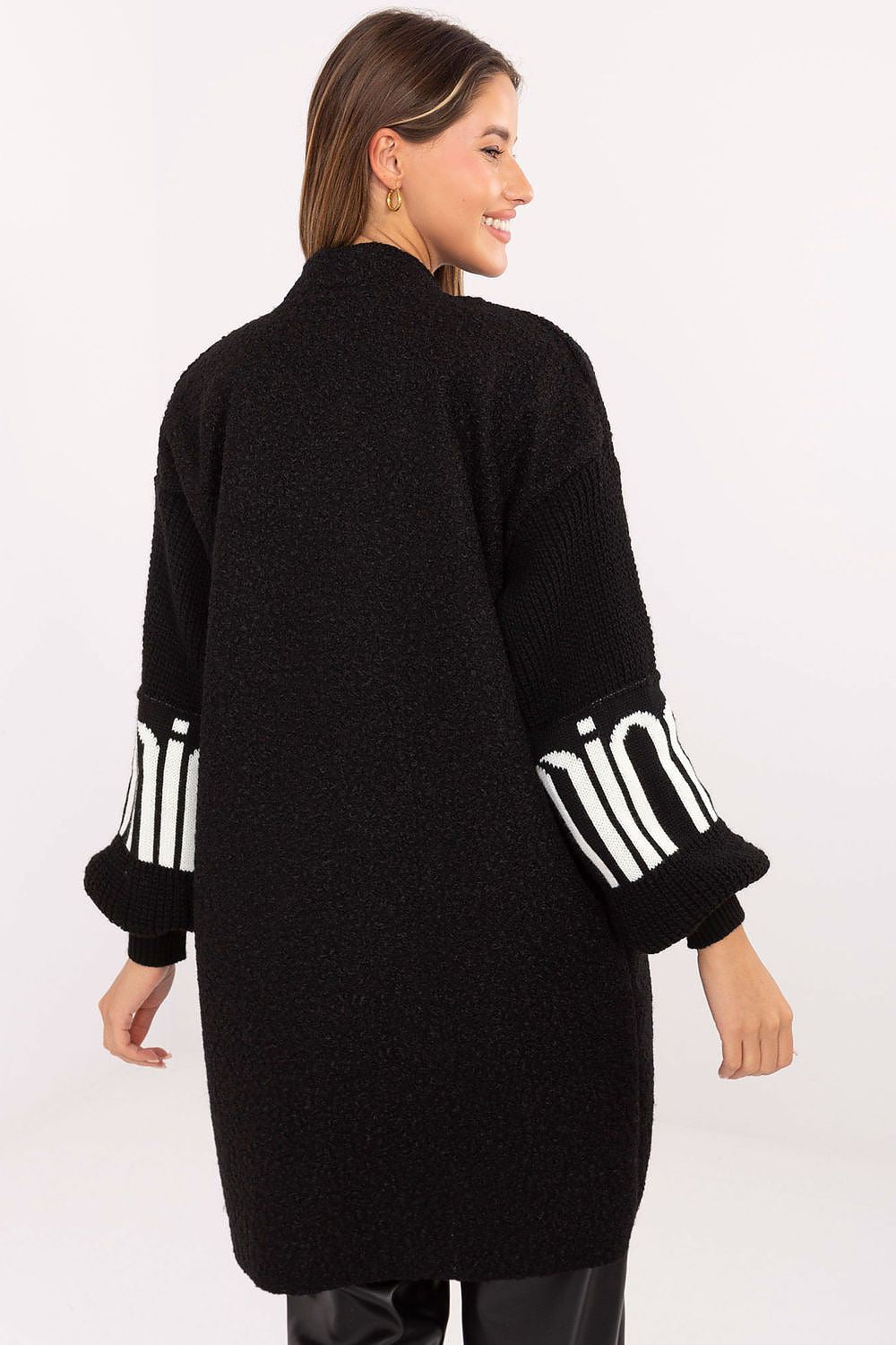Woman wearing a black cardigan with white accents on a white background