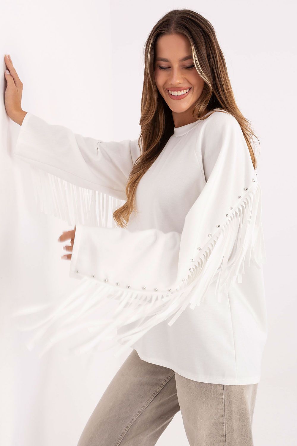 Close-up of white sweatshirt’s decorative fringes and studs