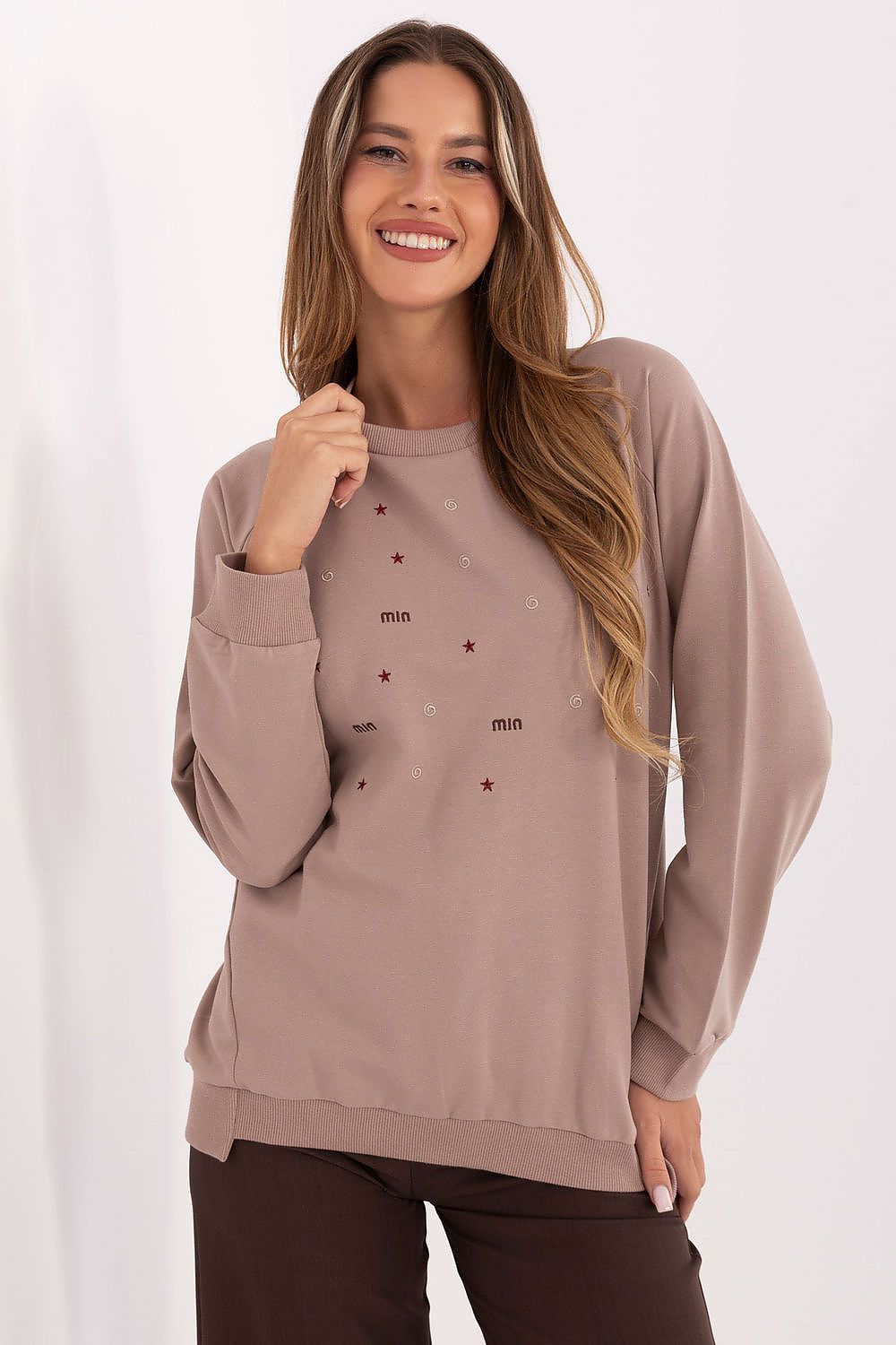 Woman wearing a brown sweatshirt with small red patterns on a white background