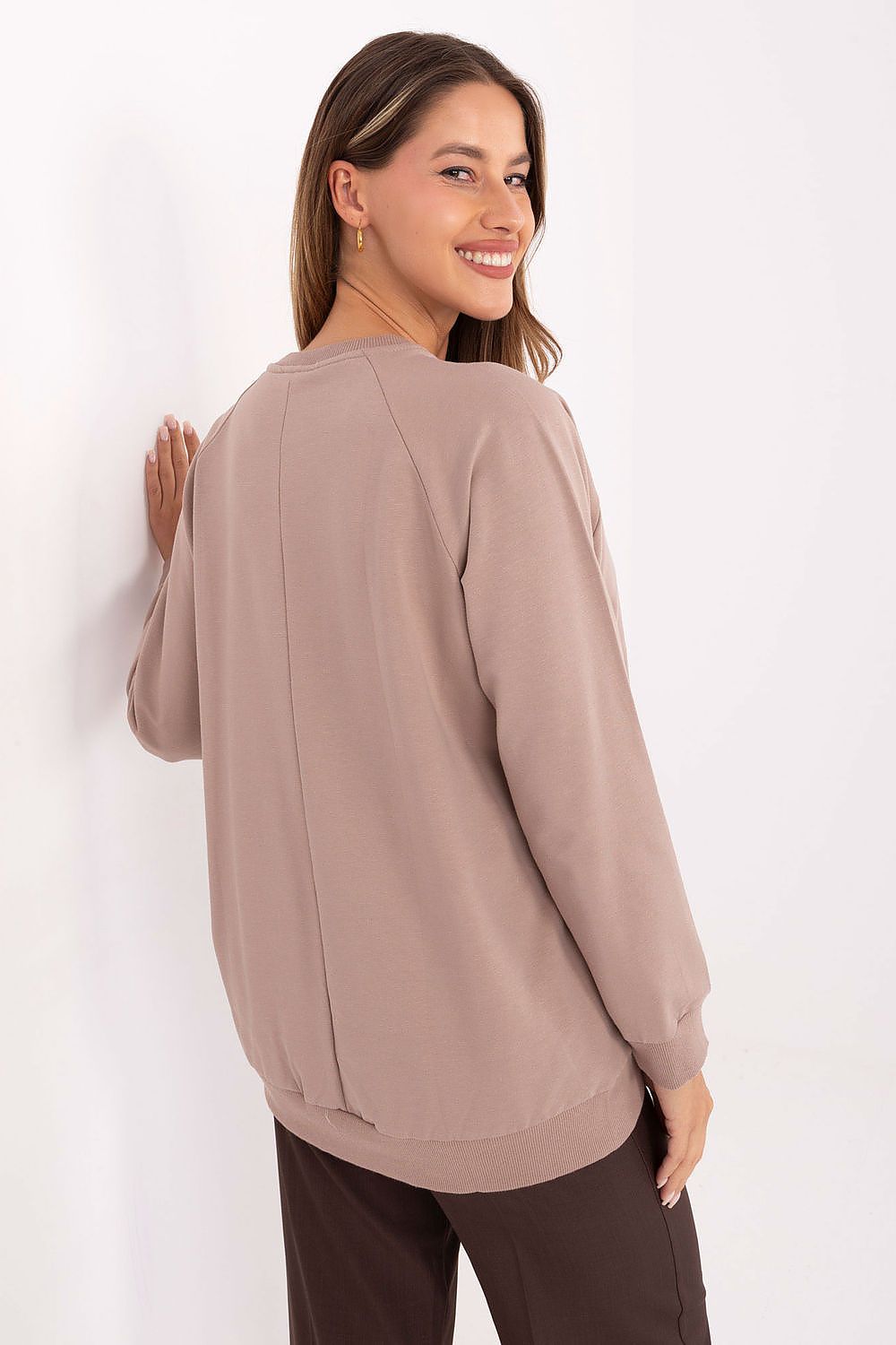 Woman wearing a beige sweater against a white background