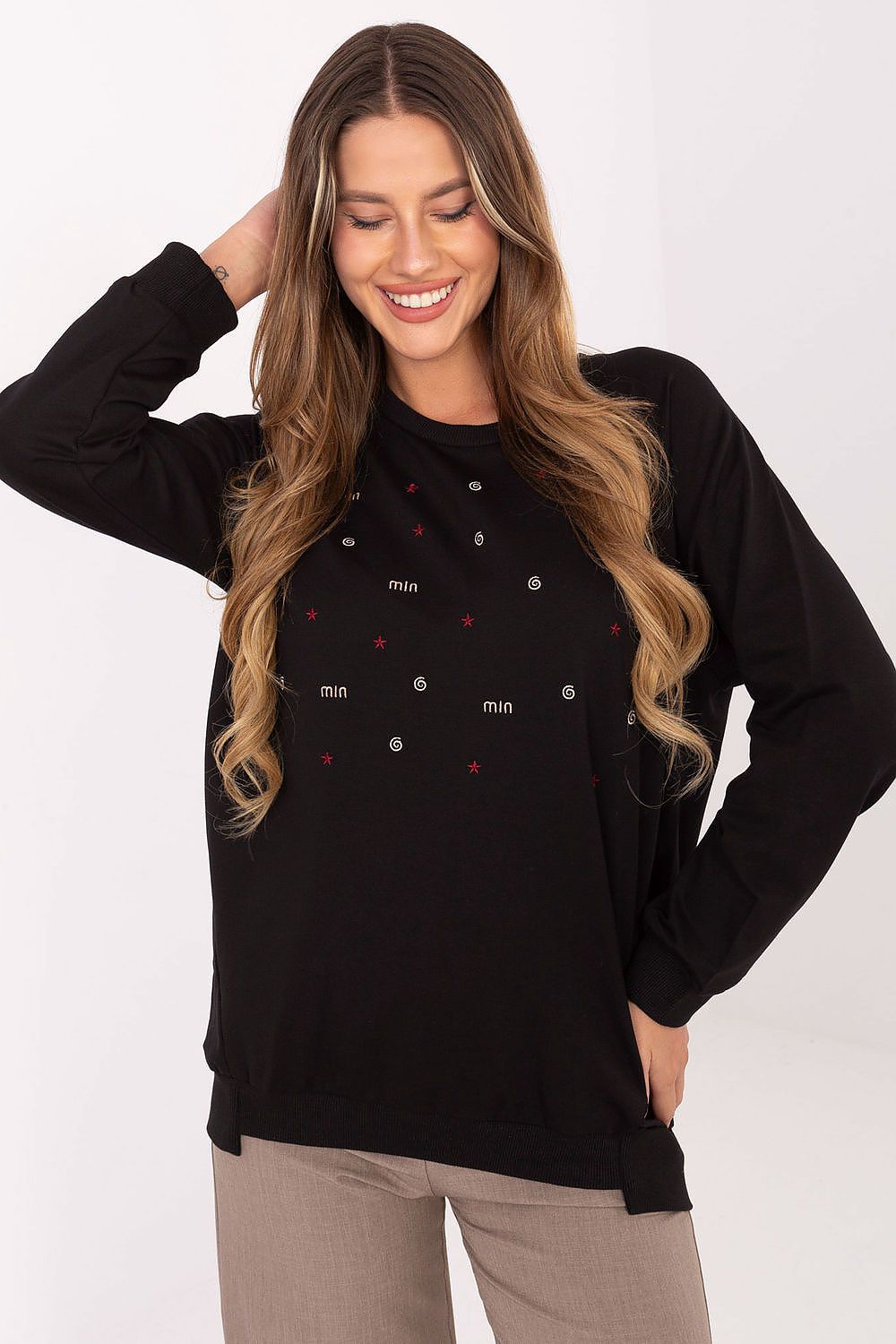 Woman wearing a black long-sleeve top with small red and white patterns on a white background