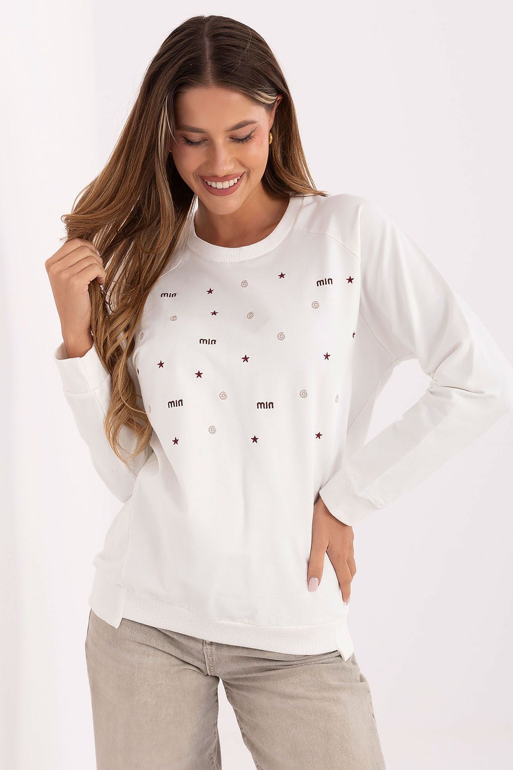 Woman wearing a white long-sleeve shirt with star patterns on a plain background