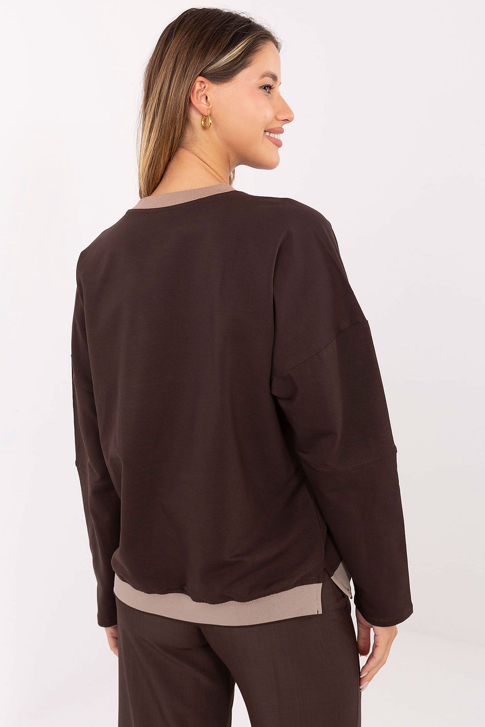 Woman wearing a brown sweater and pants on a white background
