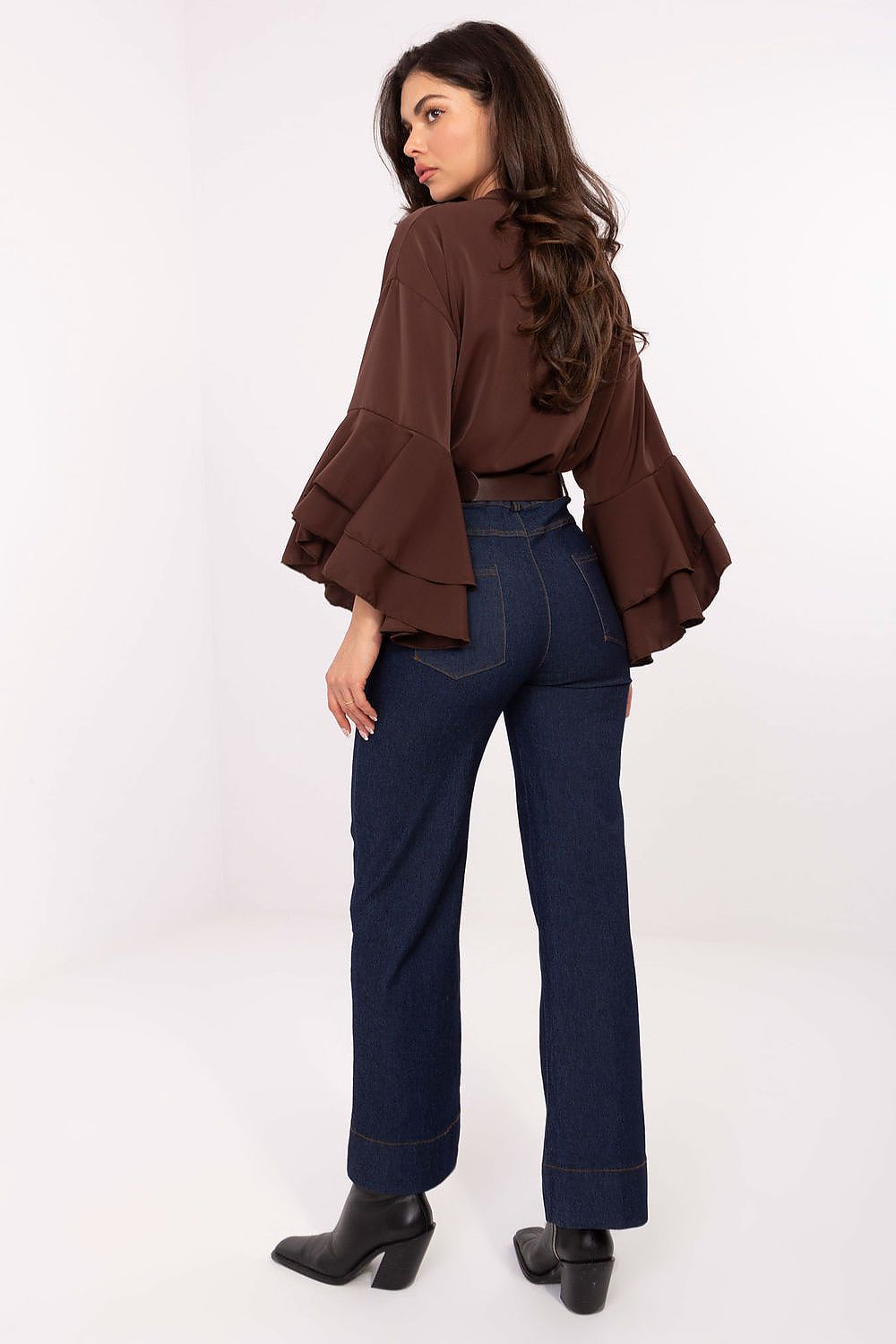 Woman wearing a brown blouse and blue jeans on a white background