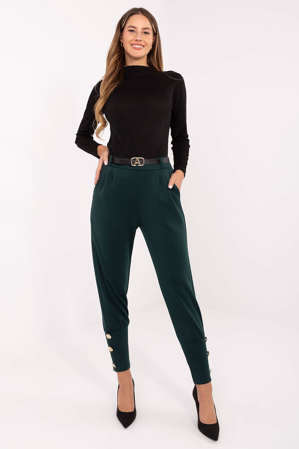 Woman wearing a black top and green pants on a white background
