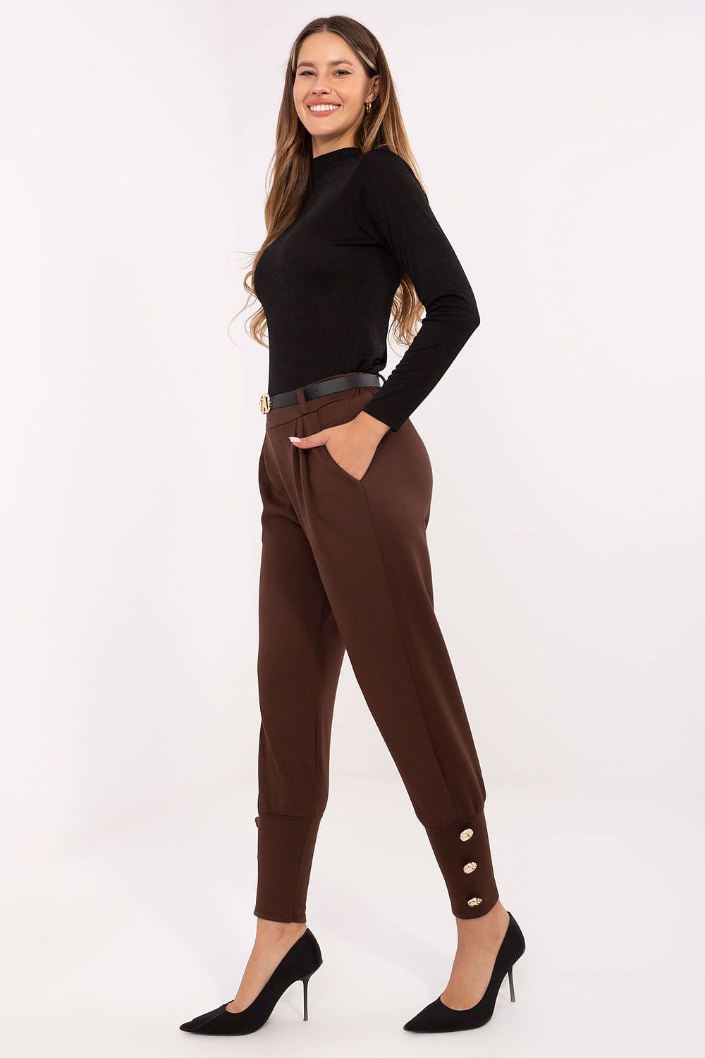 Woman wearing a black top and brown pants with buttons on a white background