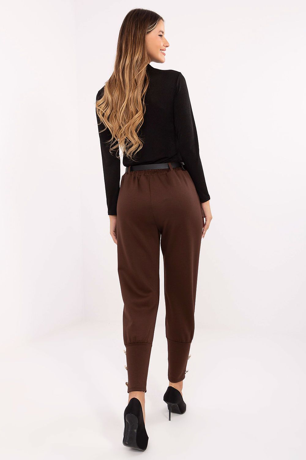 Woman wearing a black top and brown pants on a white background