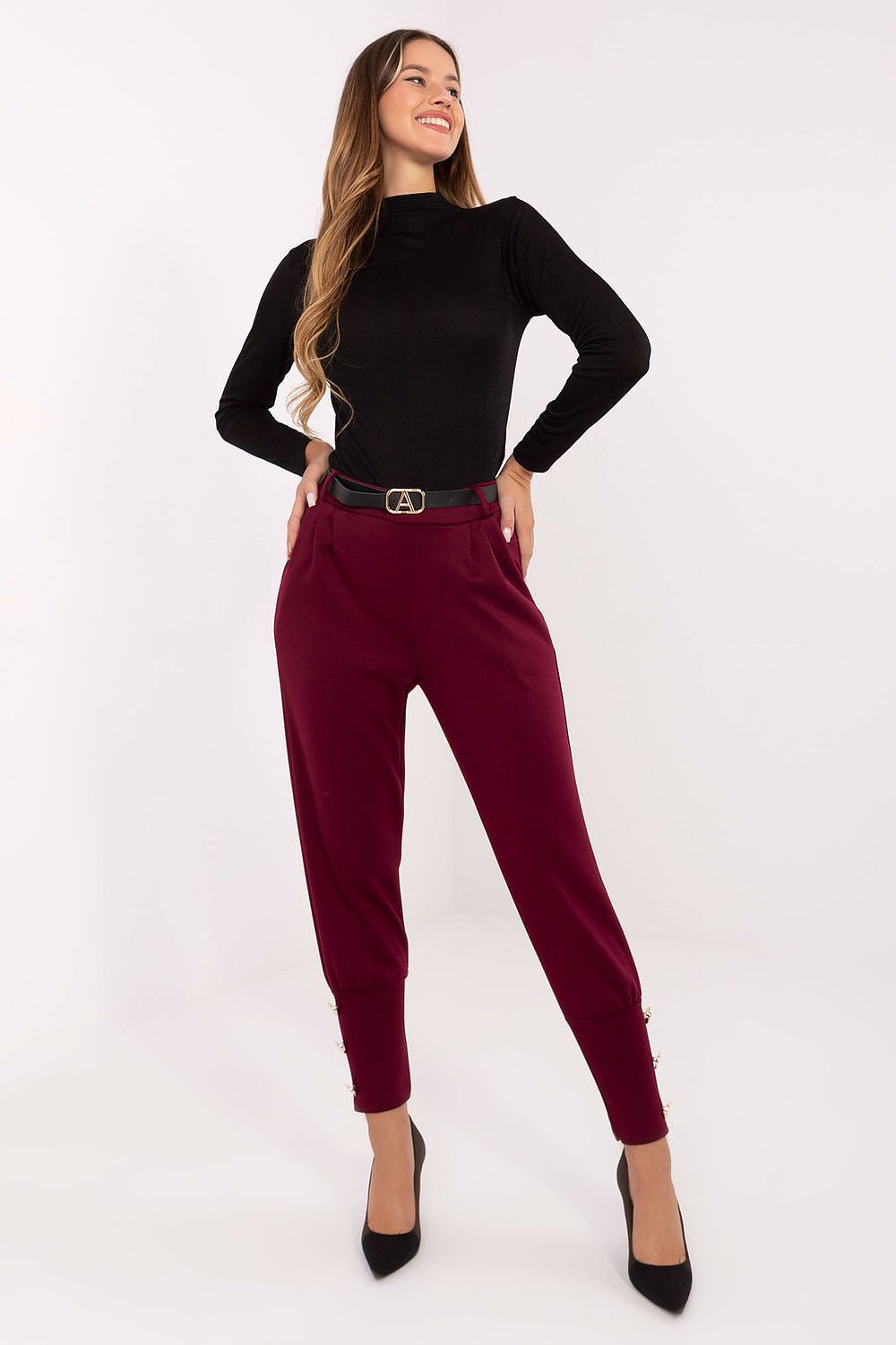 Woman wearing a black top and burgundy pants on a white background