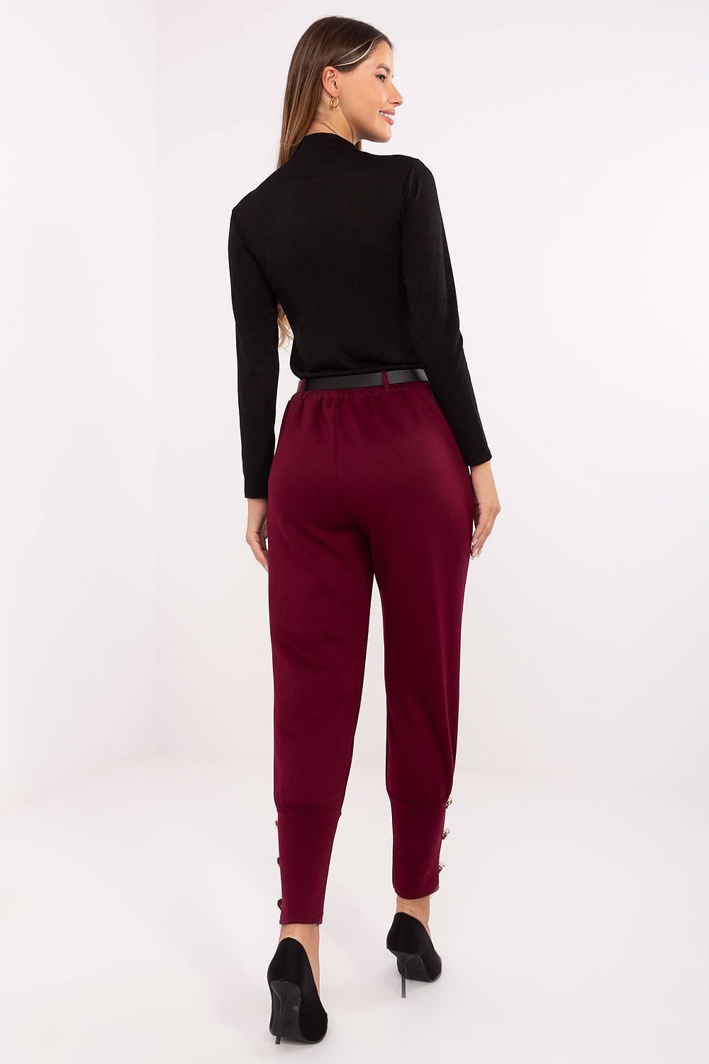Woman wearing a black top and burgundy pants on a white background