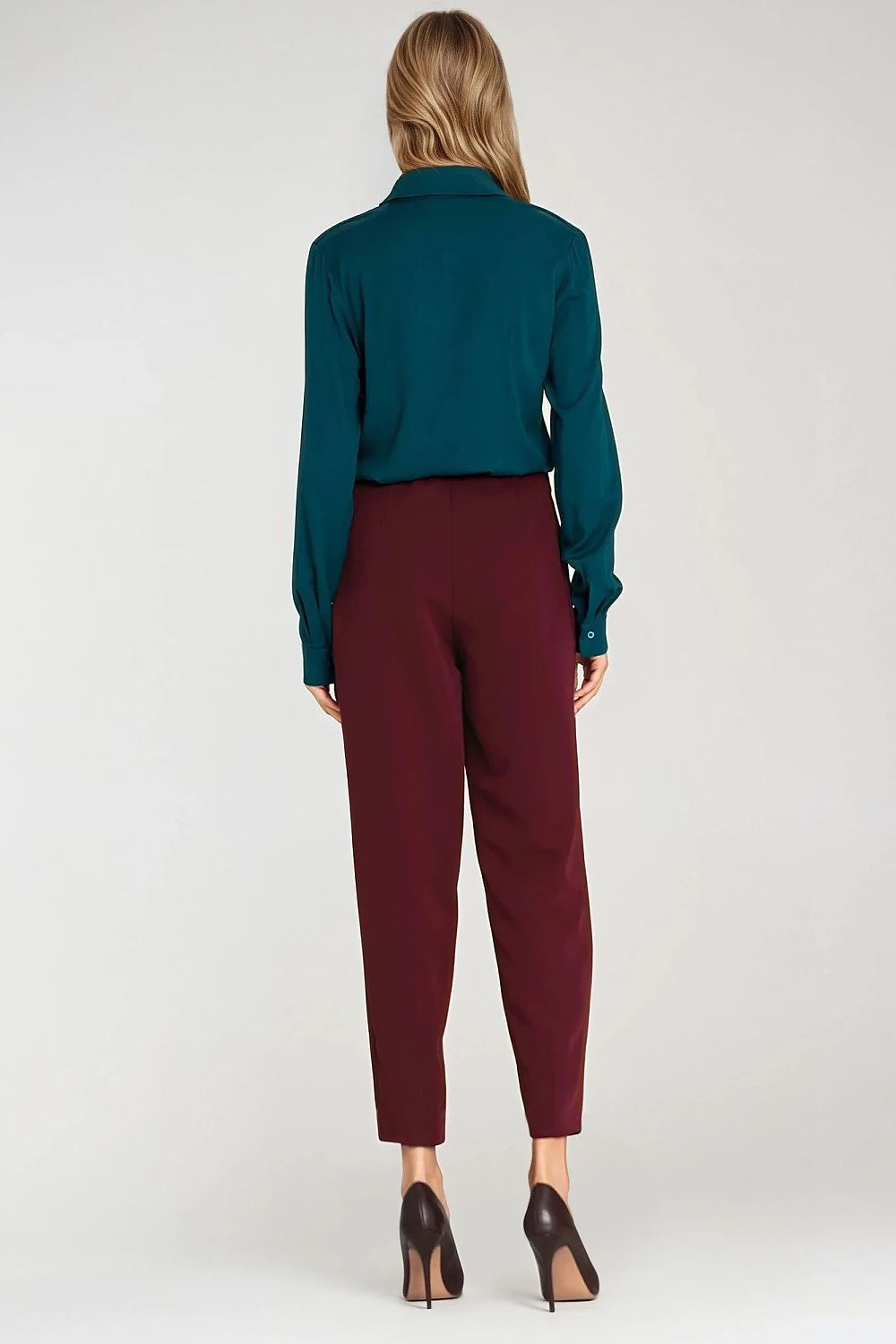 Person wearing a teal blouse and burgundy pants on a white background