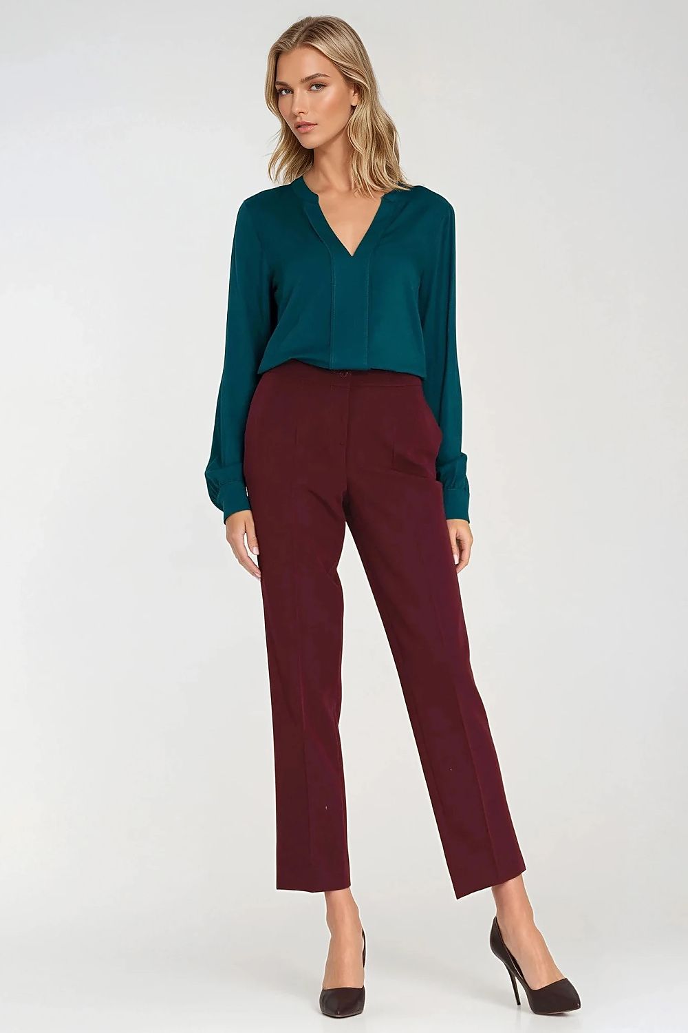 Woman wearing a teal blouse and burgundy pants on a white background
