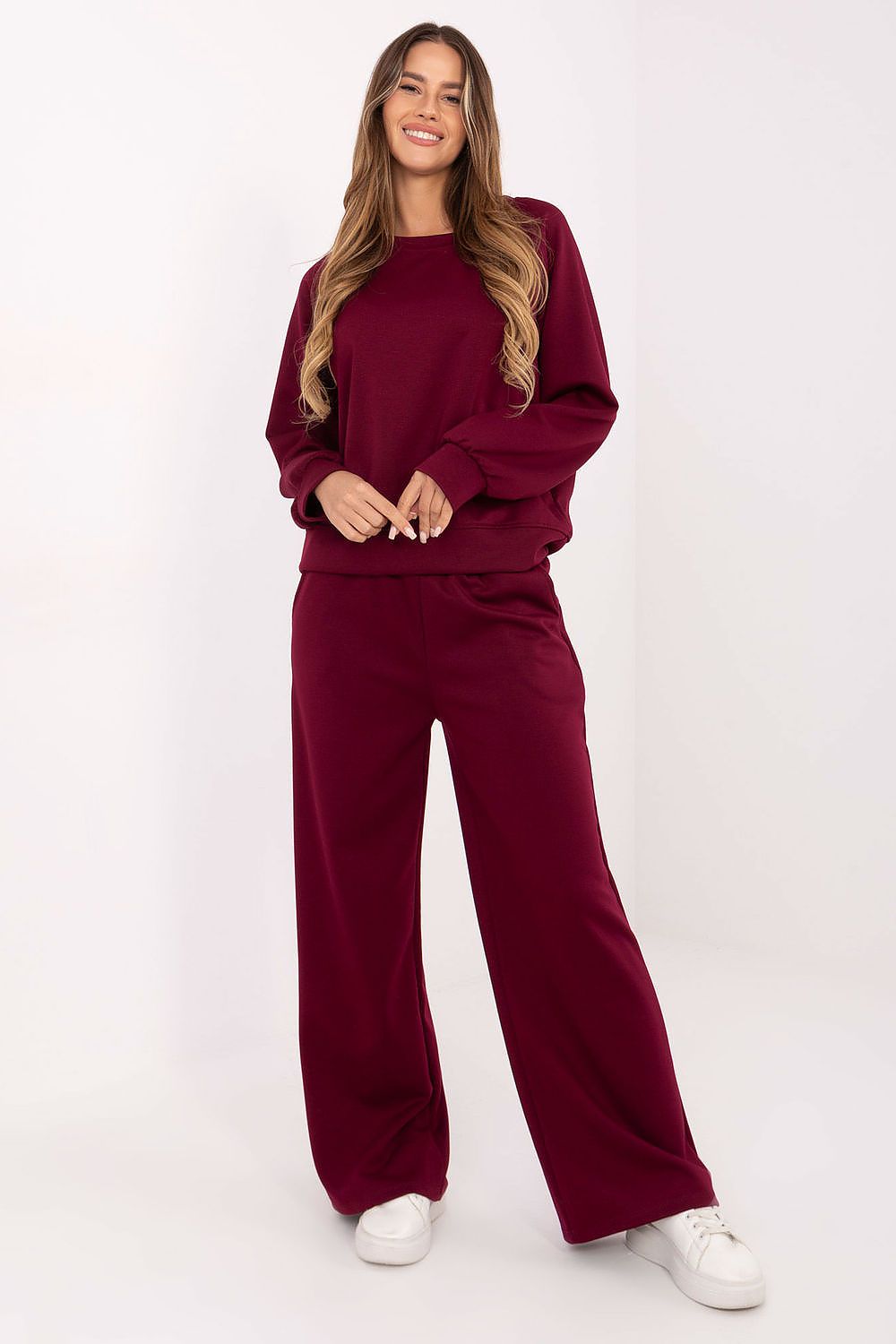 Woman wearing a burgundy tracksuit on a white background