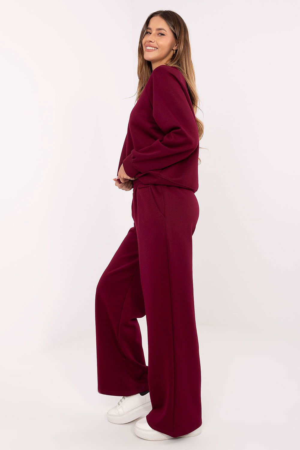 Woman wearing a burgundy outfit with wide-leg pants on a white background