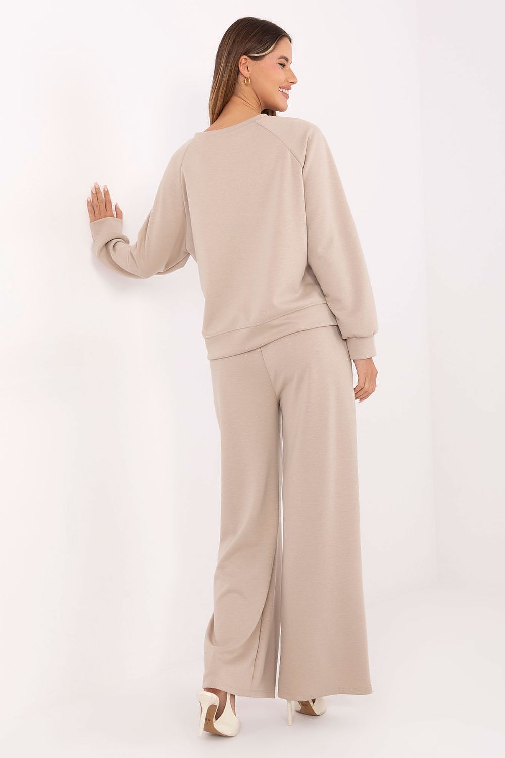 Woman wearing a beige outfit with wide-leg pants on a white background