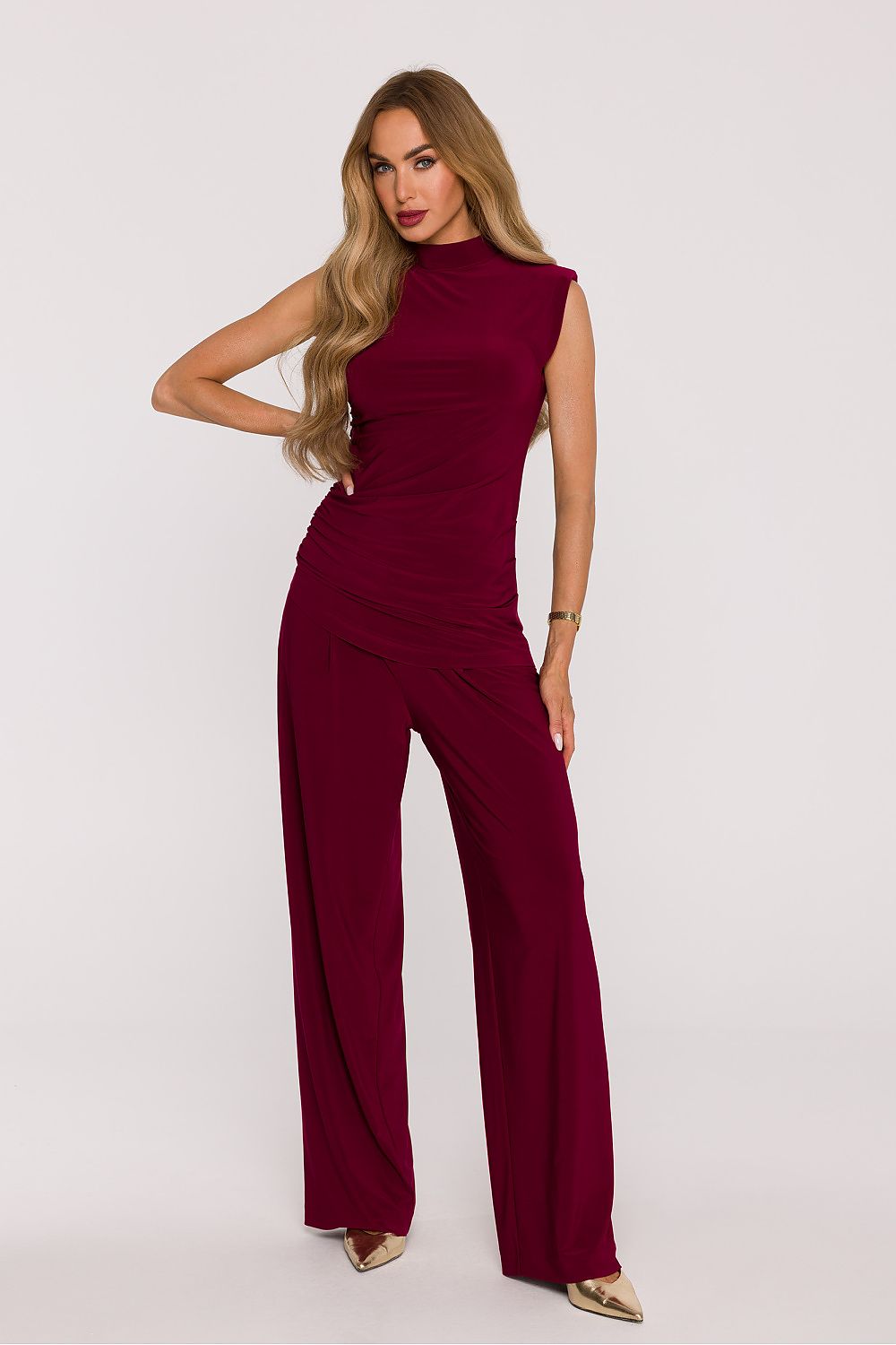 Woman wearing a burgundy jumpsuit on a white background