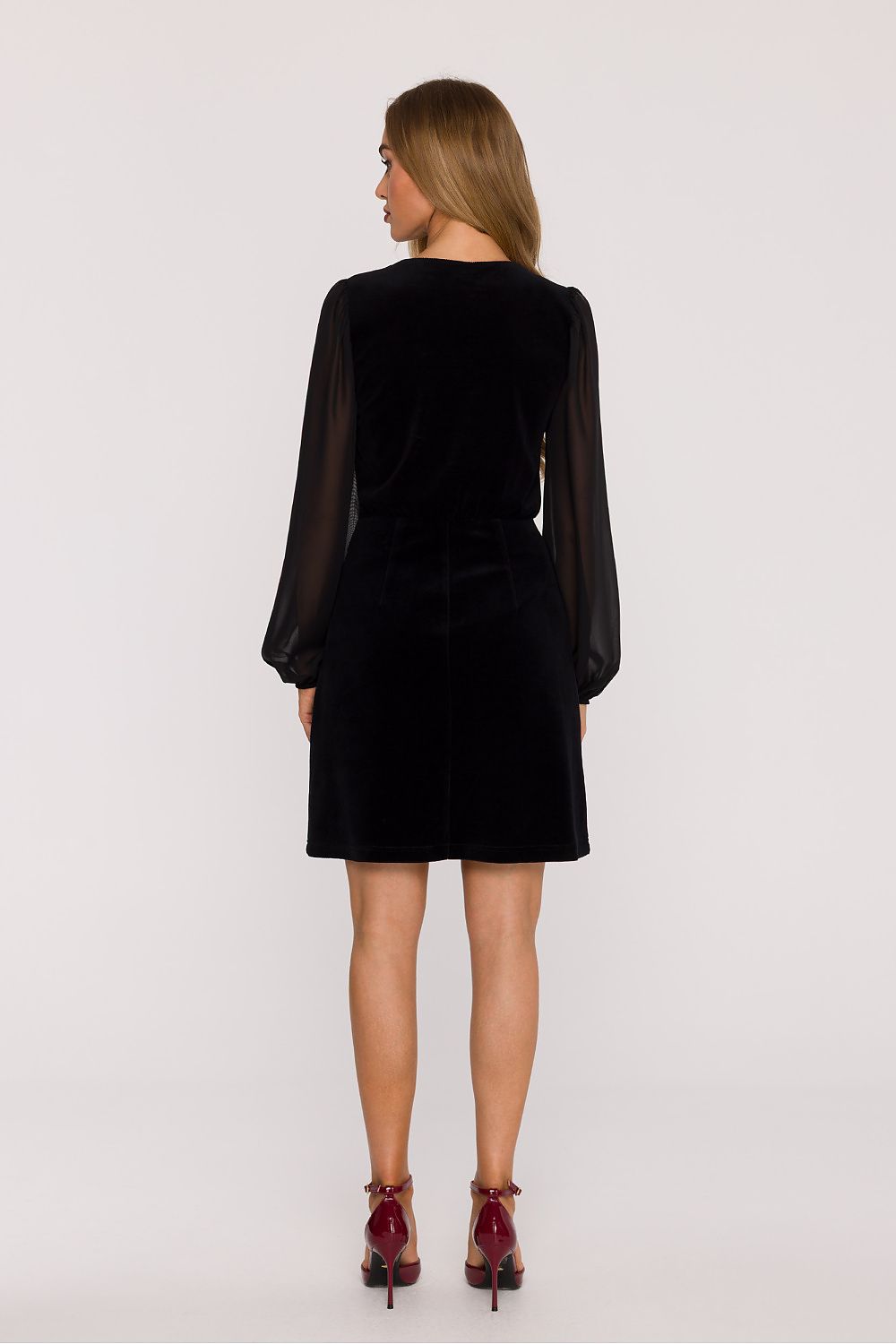 Woman wearing a black dress with sheer sleeves on a white background