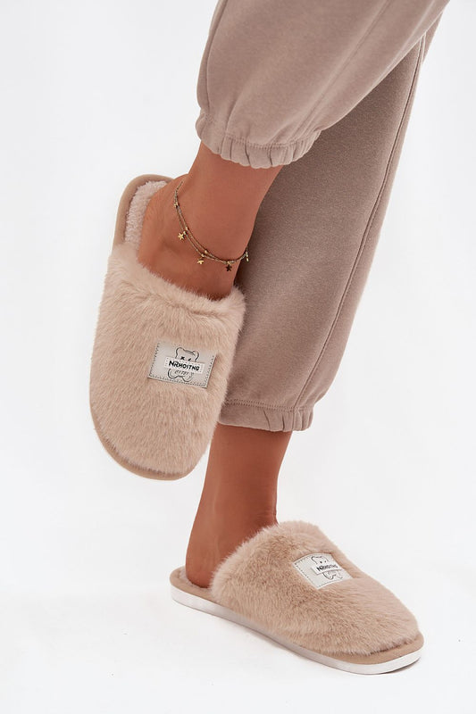 Beige slippers worn with beige pants on a white background