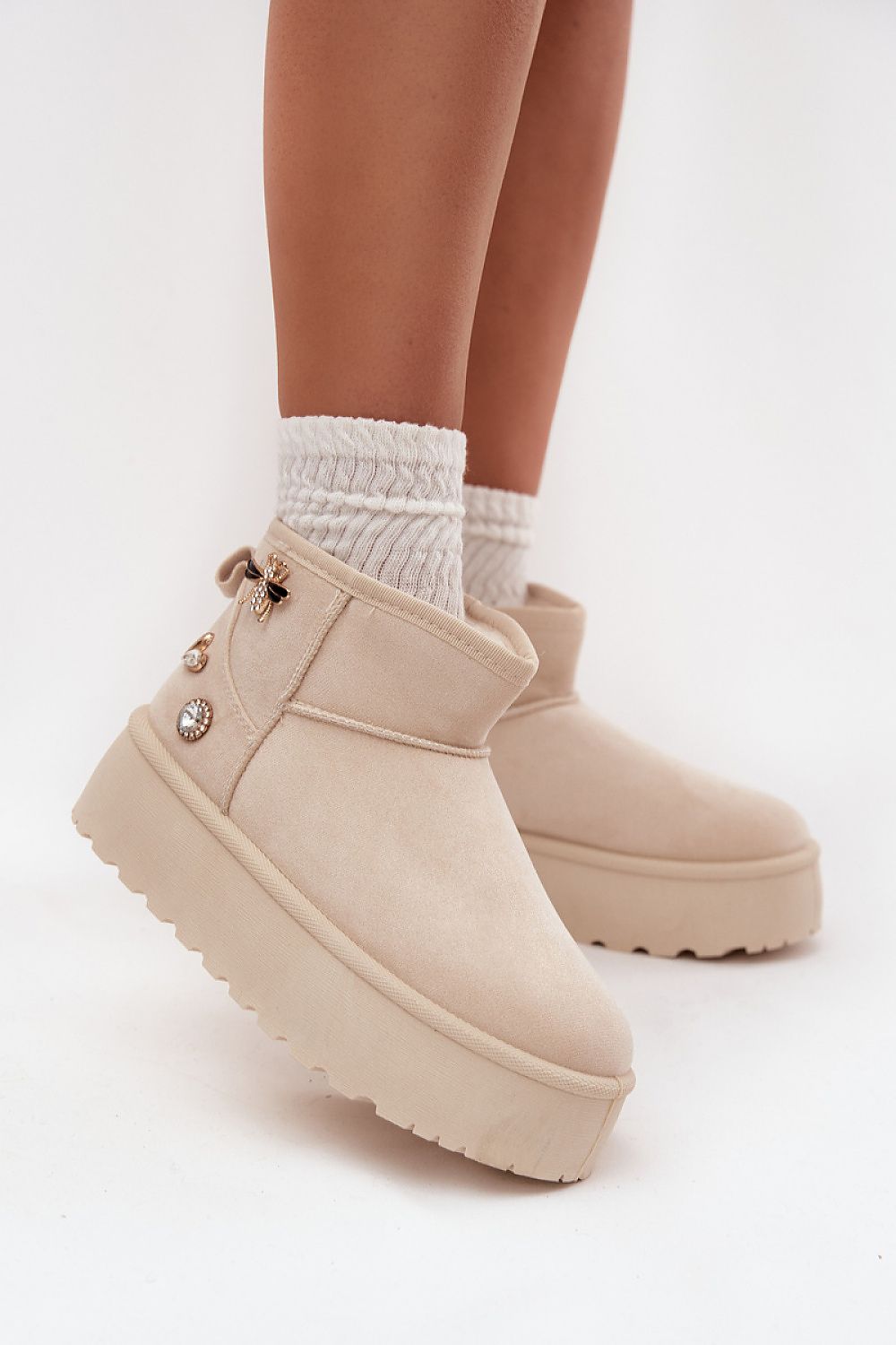 Beige faux suede snow boots with fur lining and decorative buttons on a rubber platform.