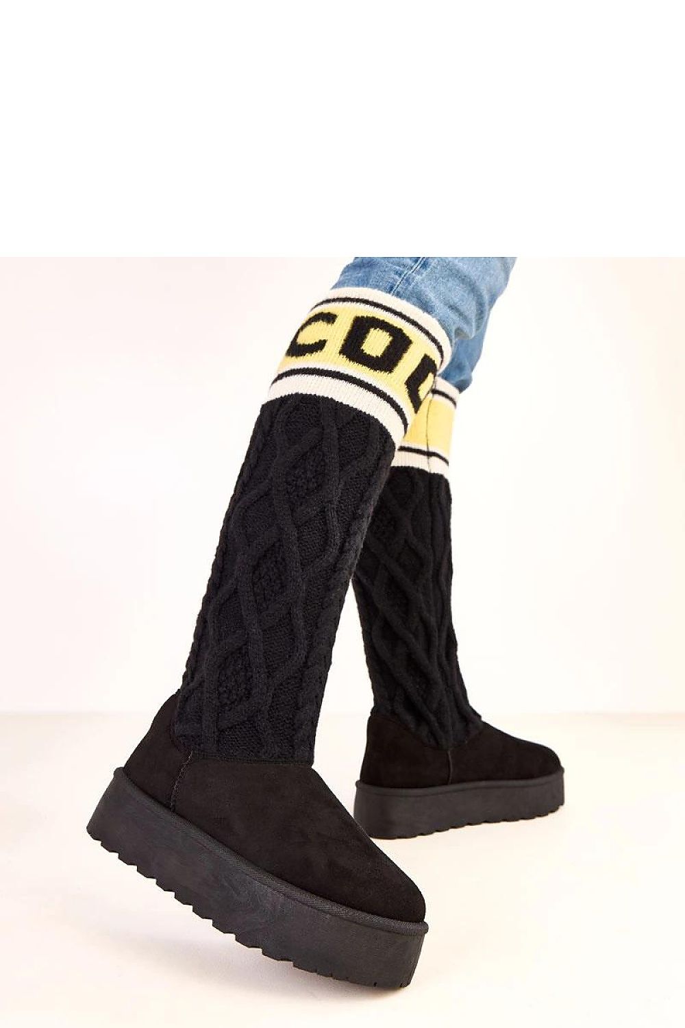 Black knee-high boots with patterned cuffs on a light background