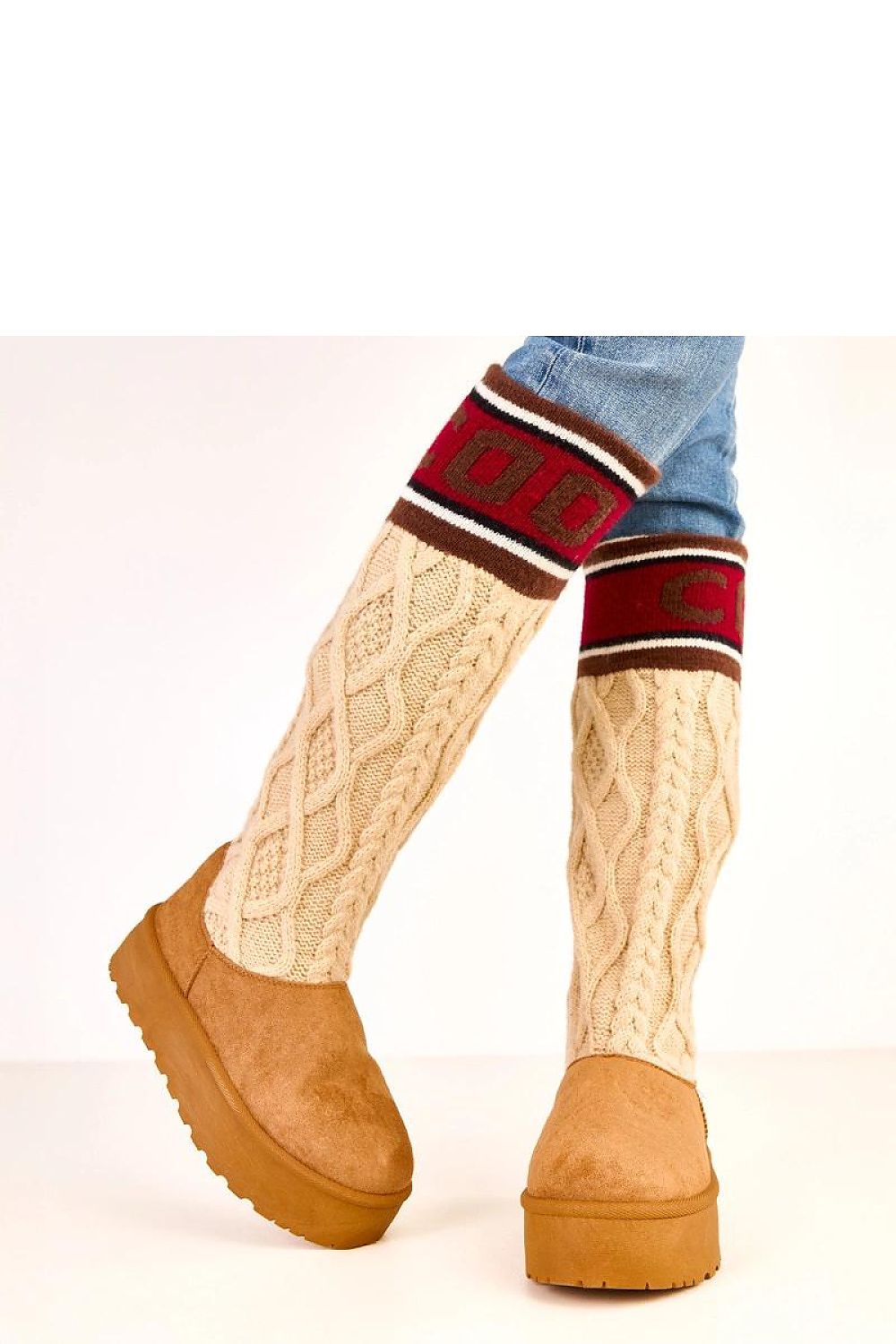 Knitted leg warmers with a pattern over brown boots on a white background
