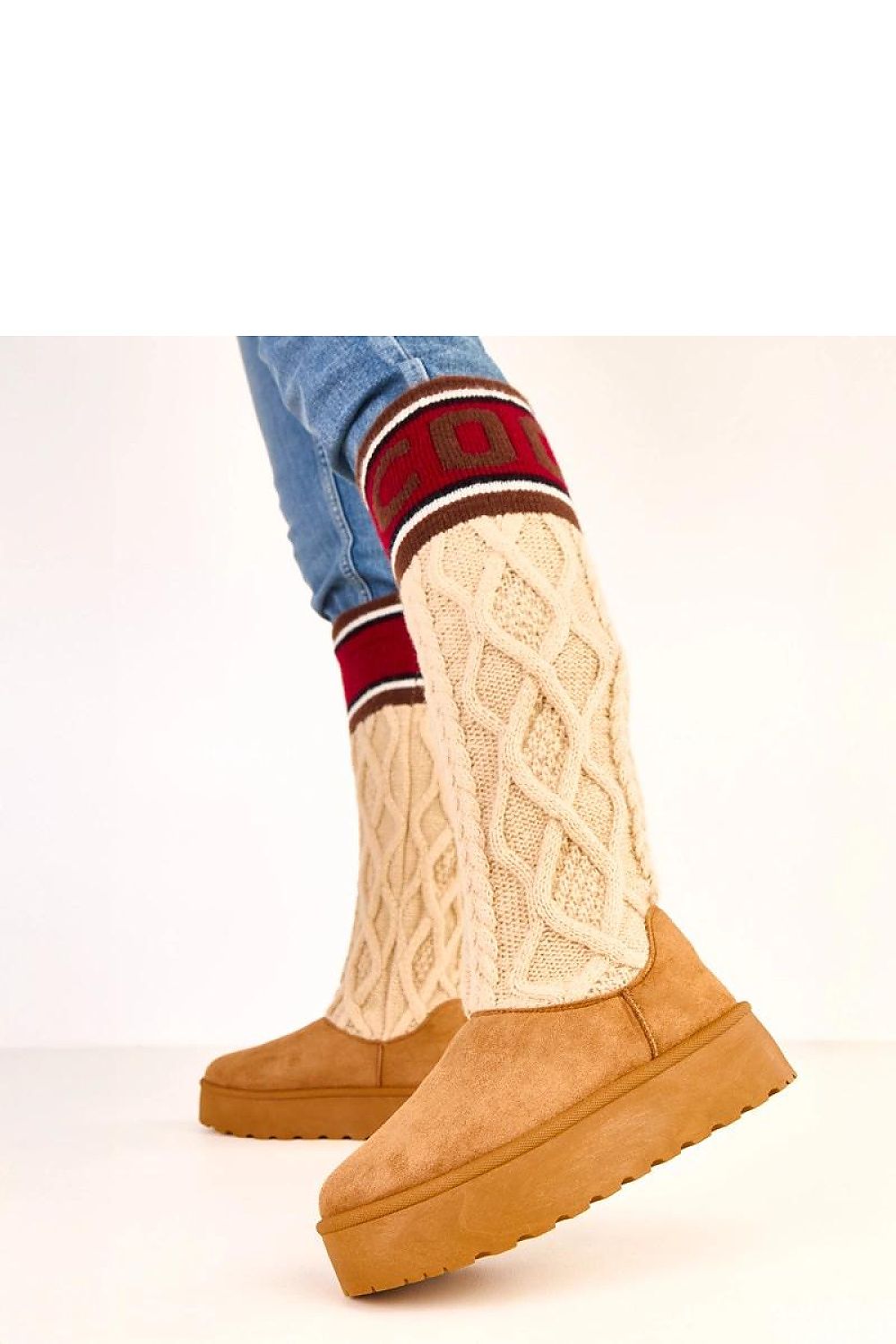 Tan platform boots with a person wearing cream knit socks and blue jeans on a white background