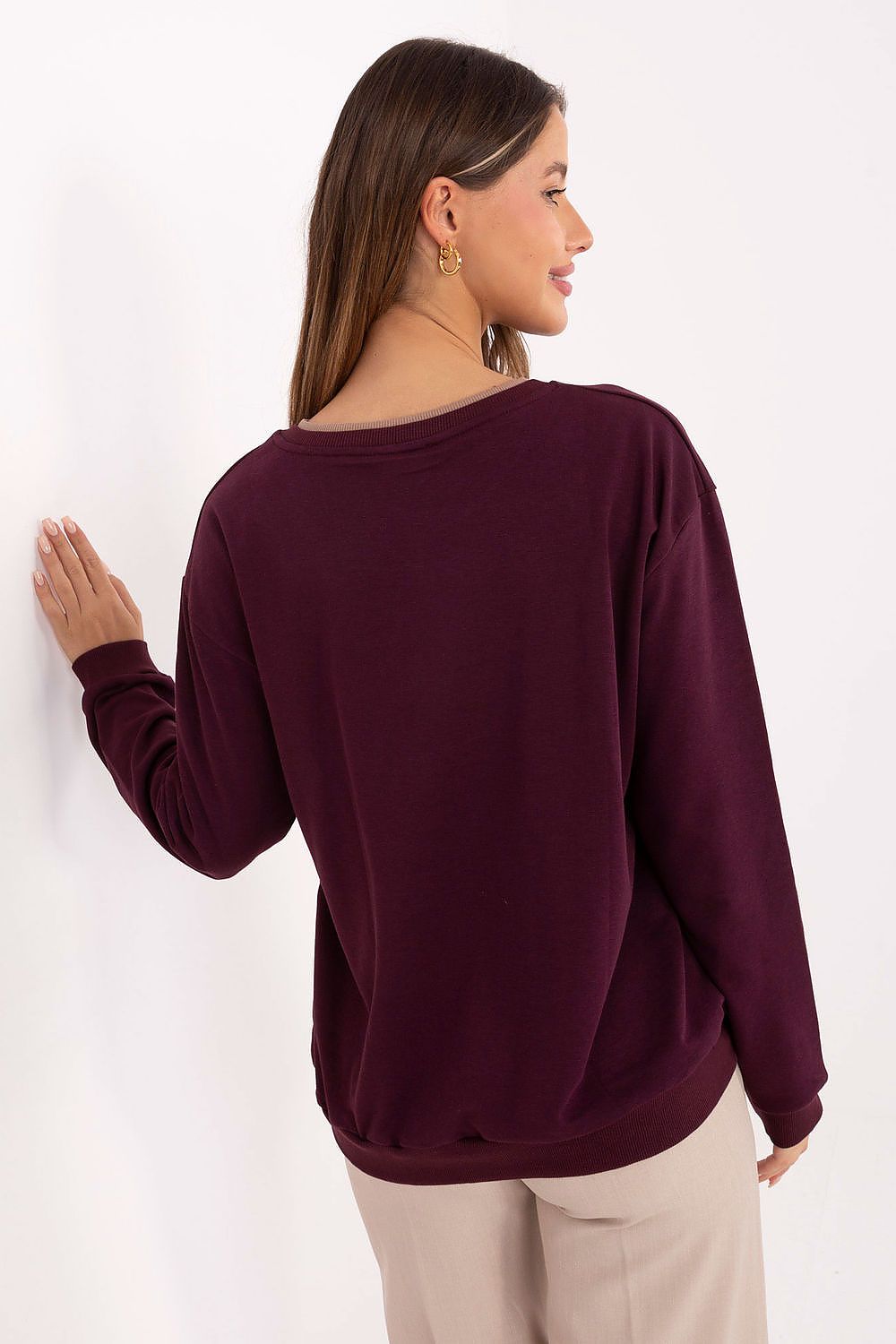 Woman wearing a burgundy sweater against a white background