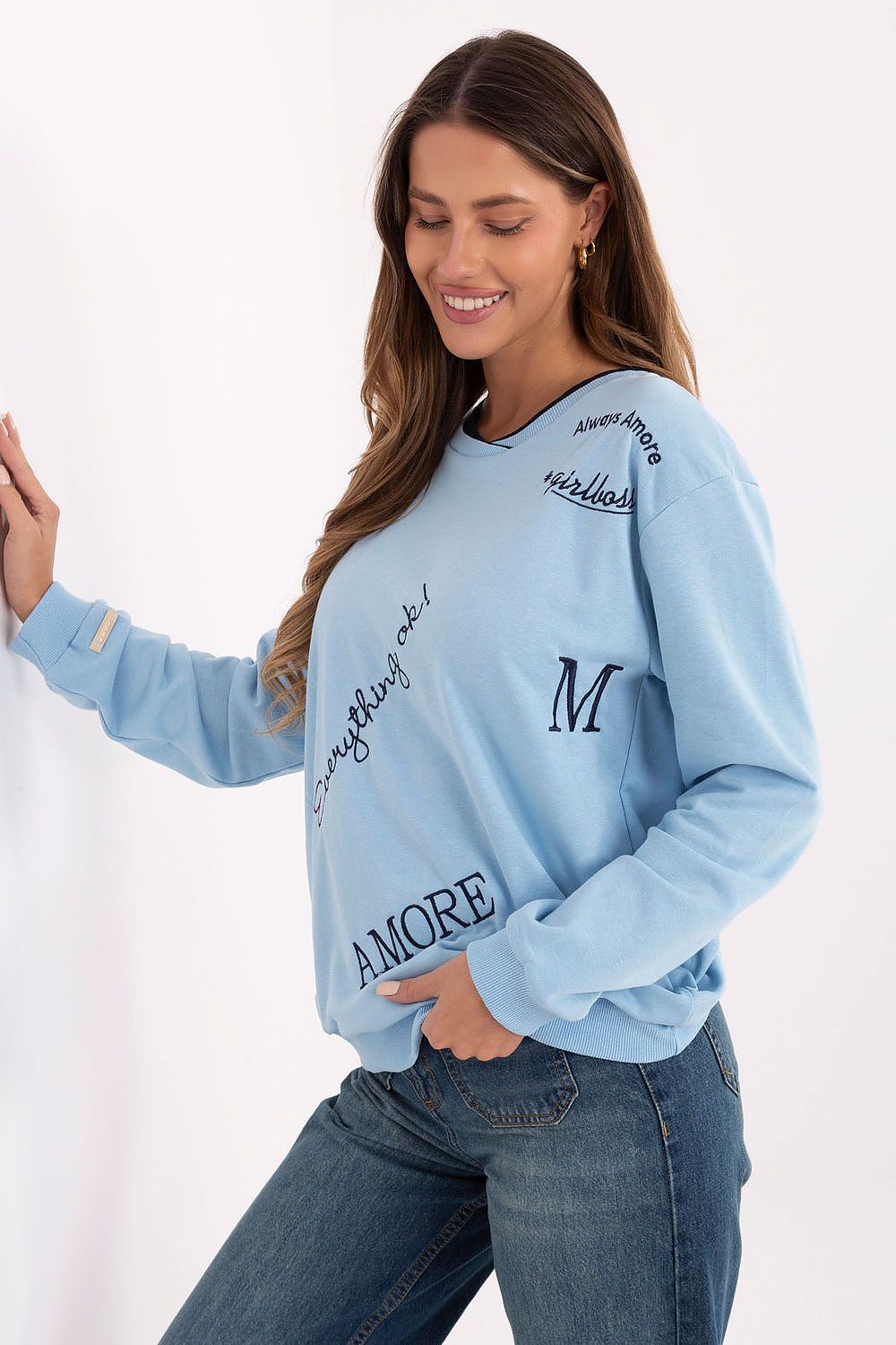 Woman wearing a light blue sweatshirt with text designs on a white background