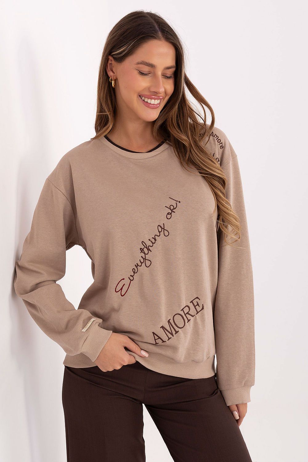 Woman wearing a beige sweatshirt with 'Everything is AMORE' text on a white background