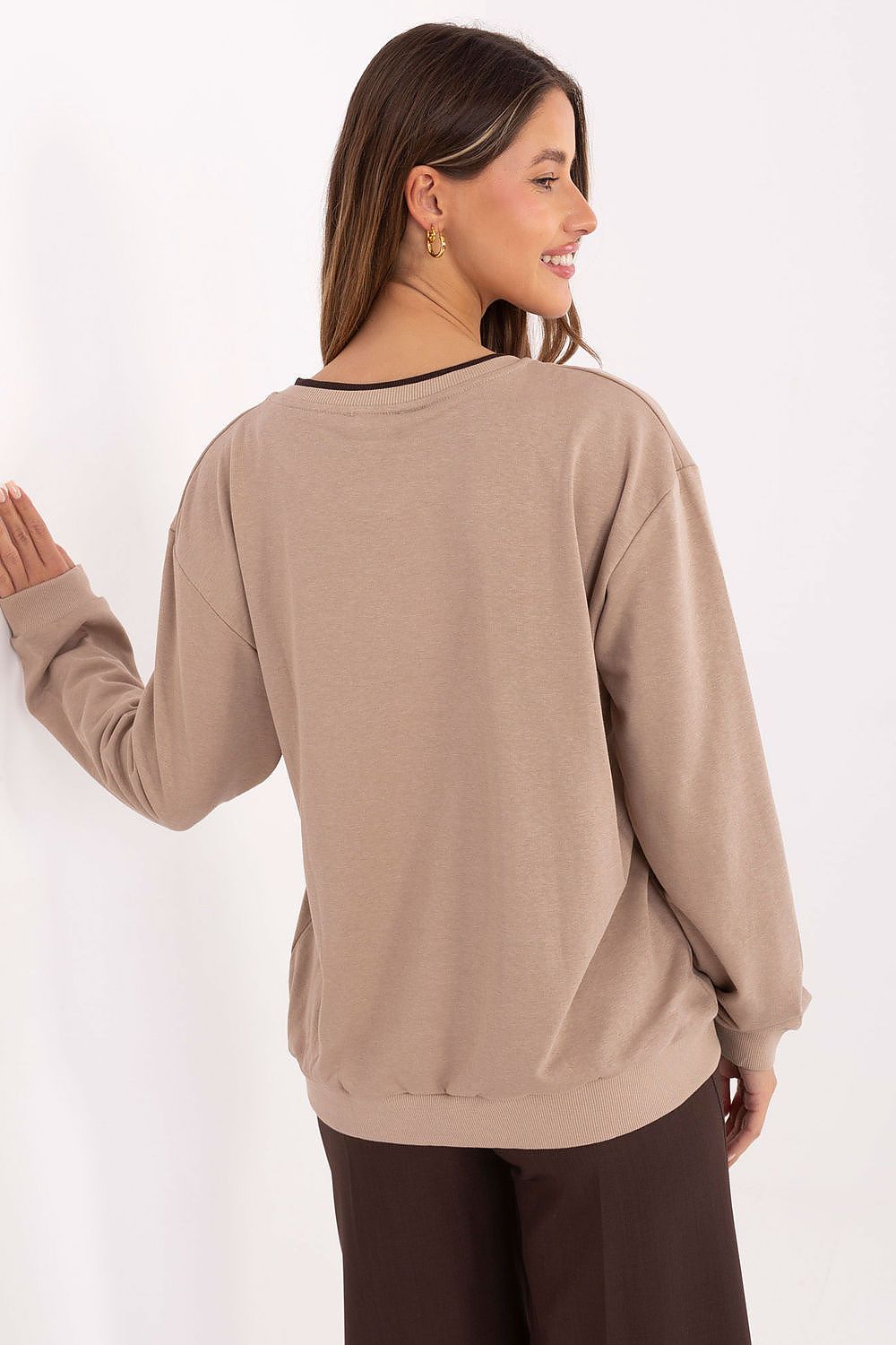Woman wearing a beige long-sleeve top against a white background
