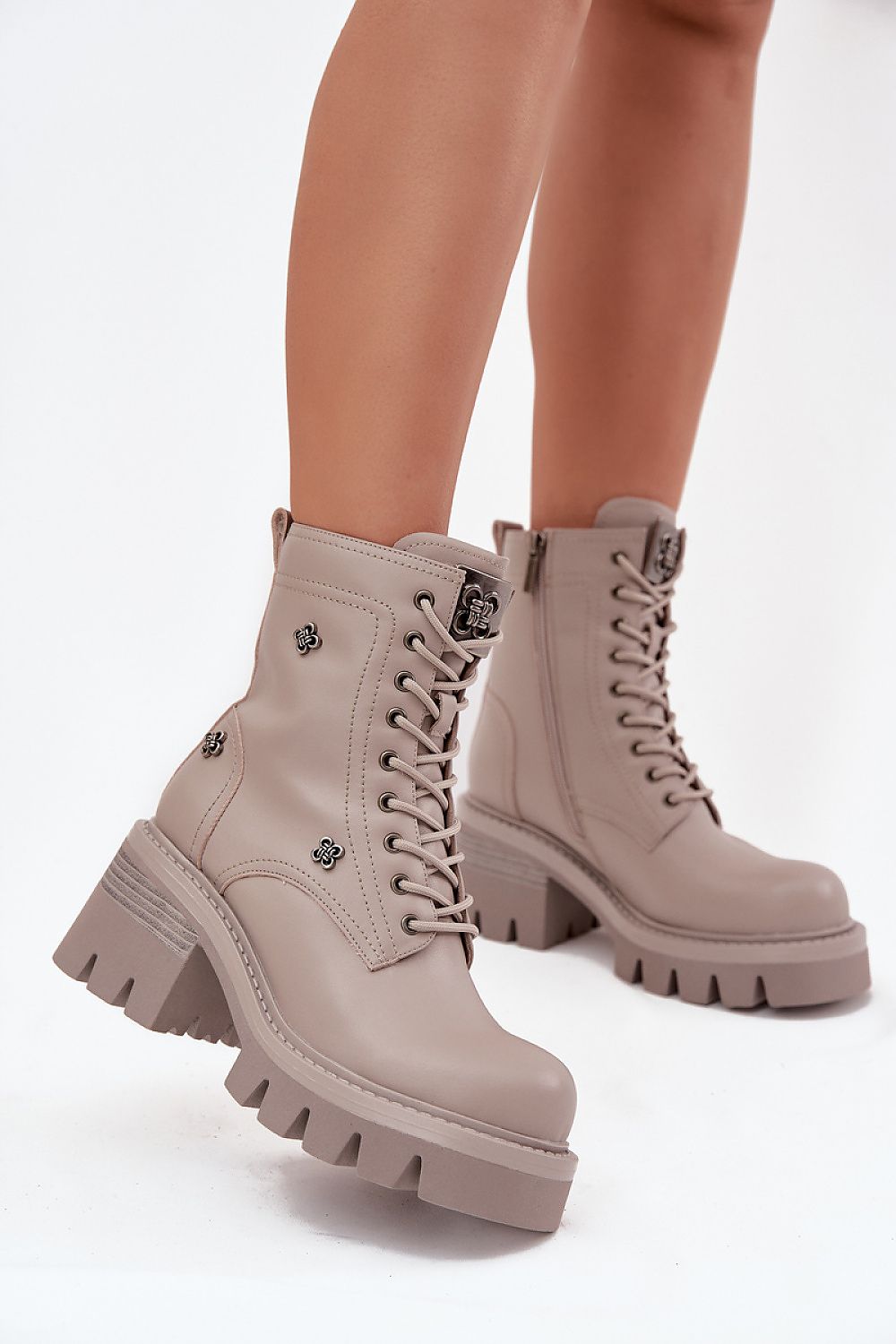 Beige combat boots worn by a person on a white background