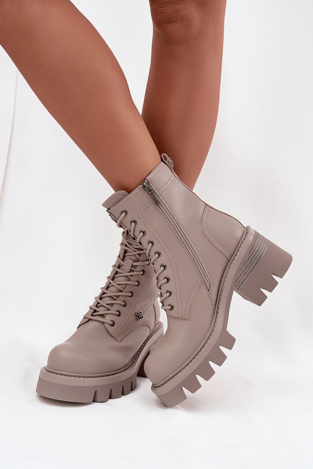 Beige combat boots worn by a person on a white background
